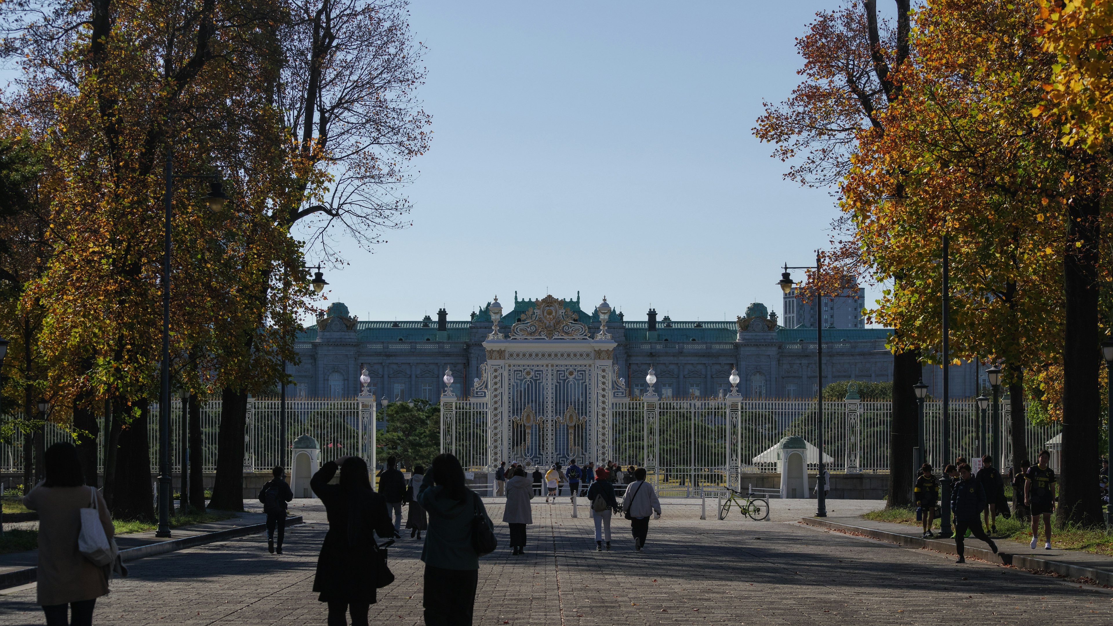 Menschen, die in einem herbstlichen Park mit einem schönen Palast im Hintergrund spazieren