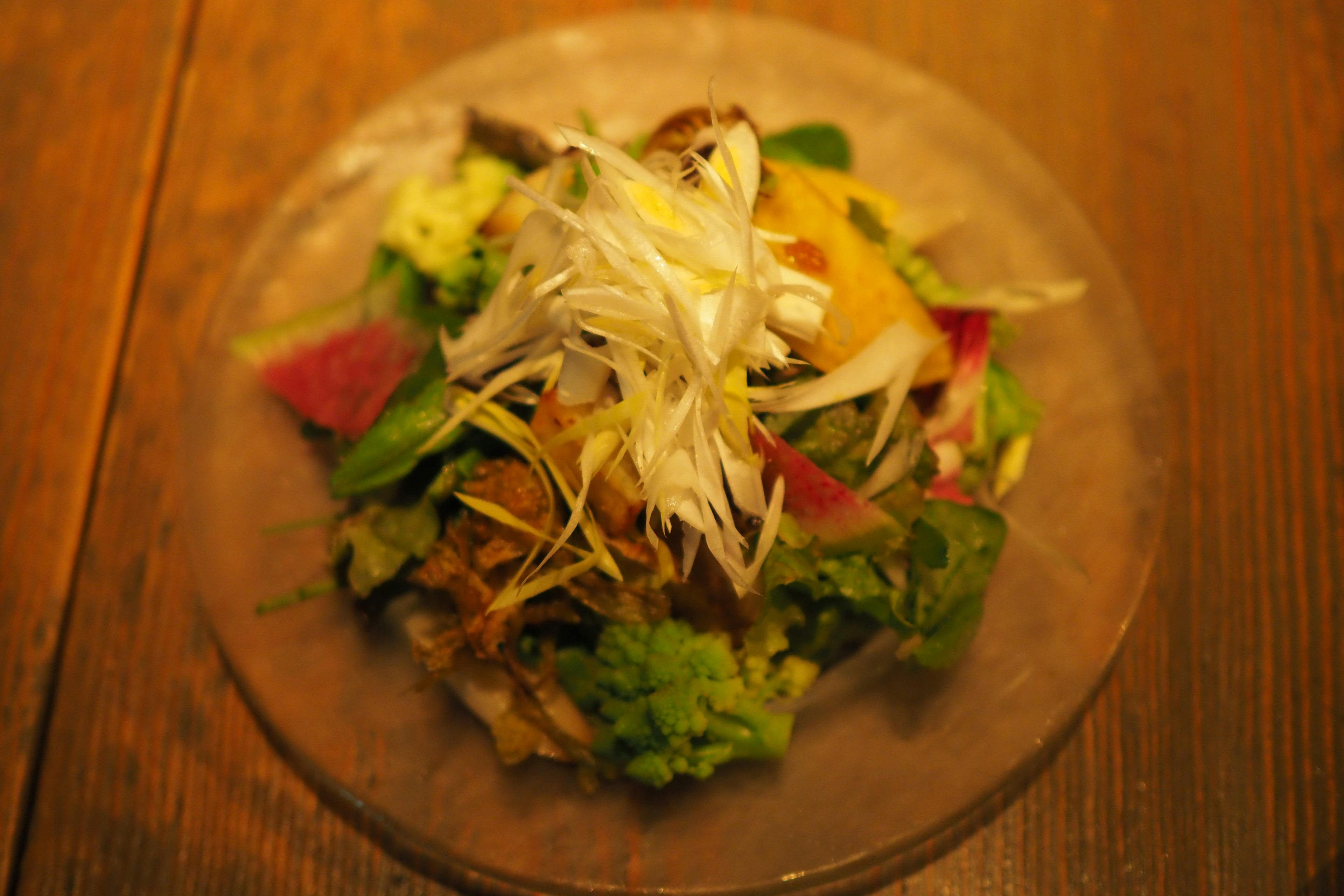 A vibrant salad topped with shredded scallions presented on a clear plate