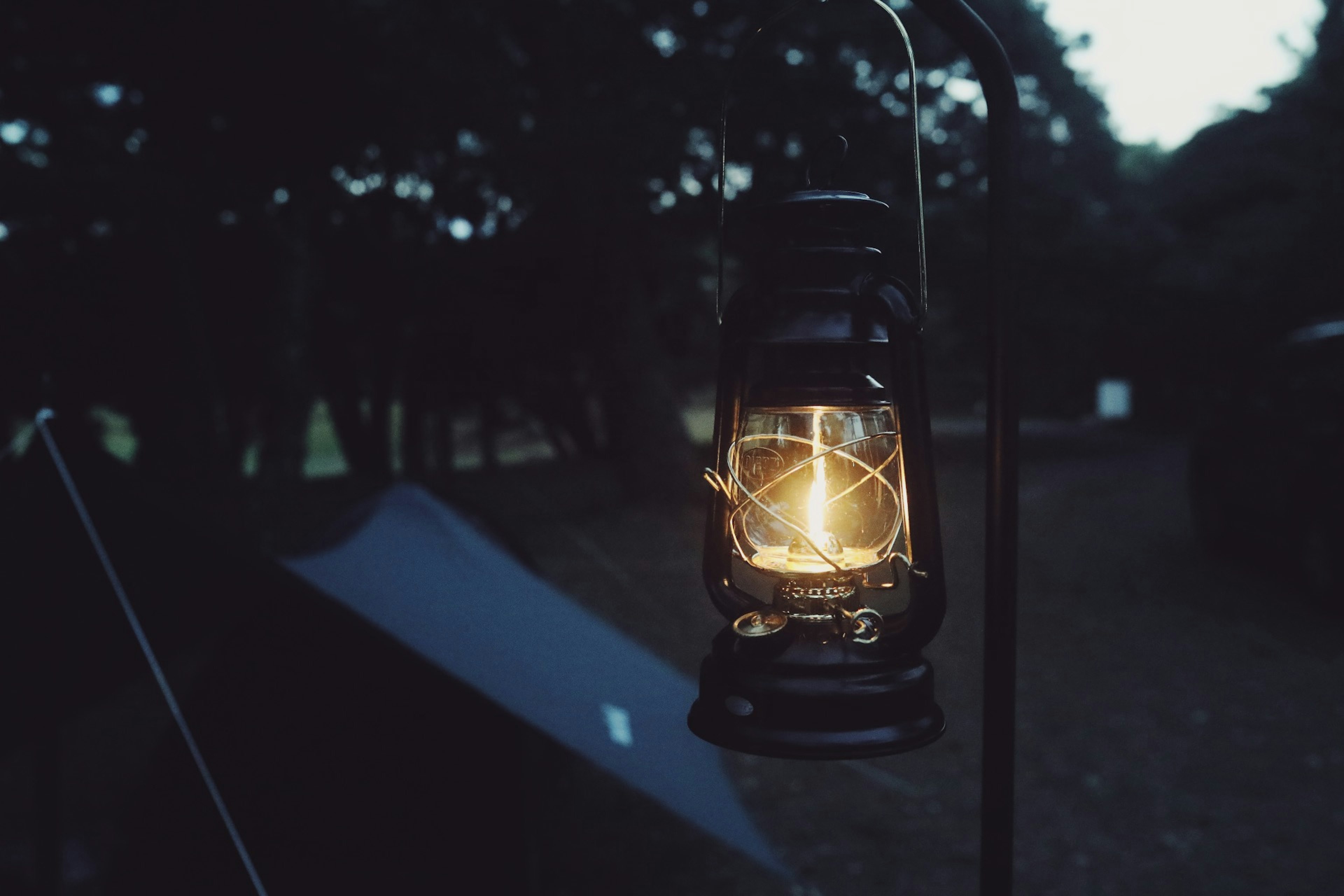 A glowing lantern hanging at a campsite during dusk