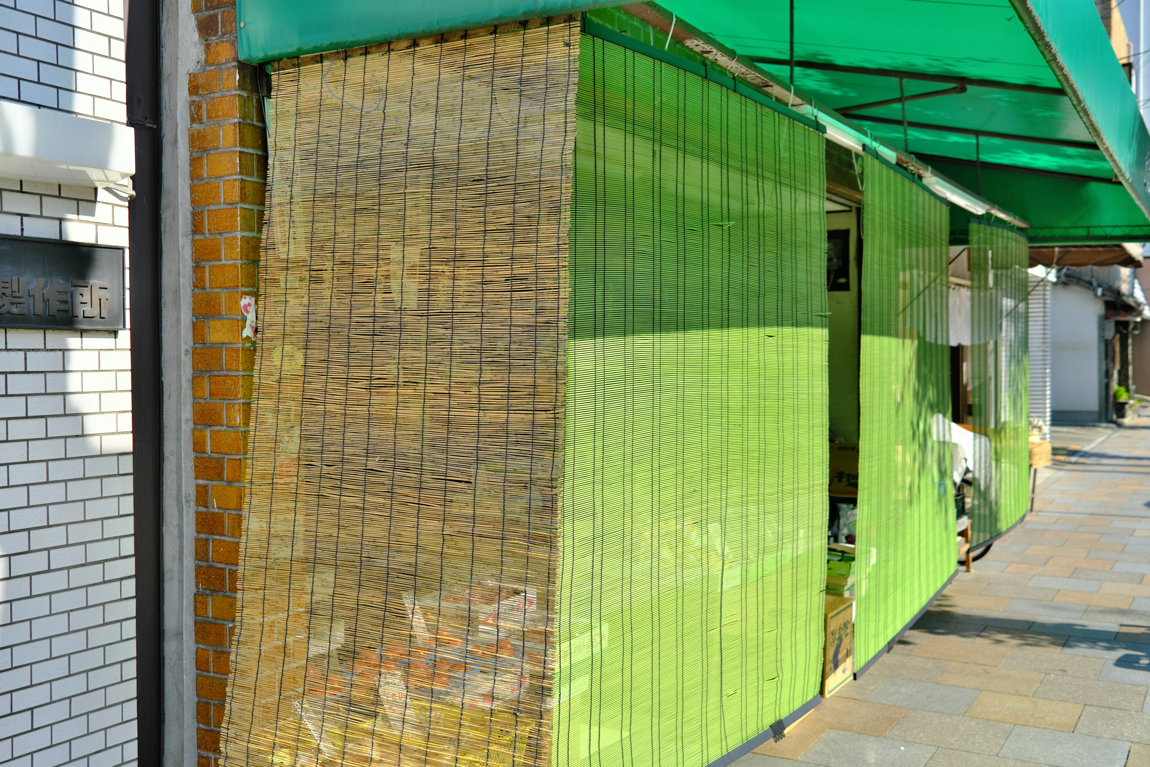 Extérieur d'un magasin avec des murs verts et une couverture en bambou