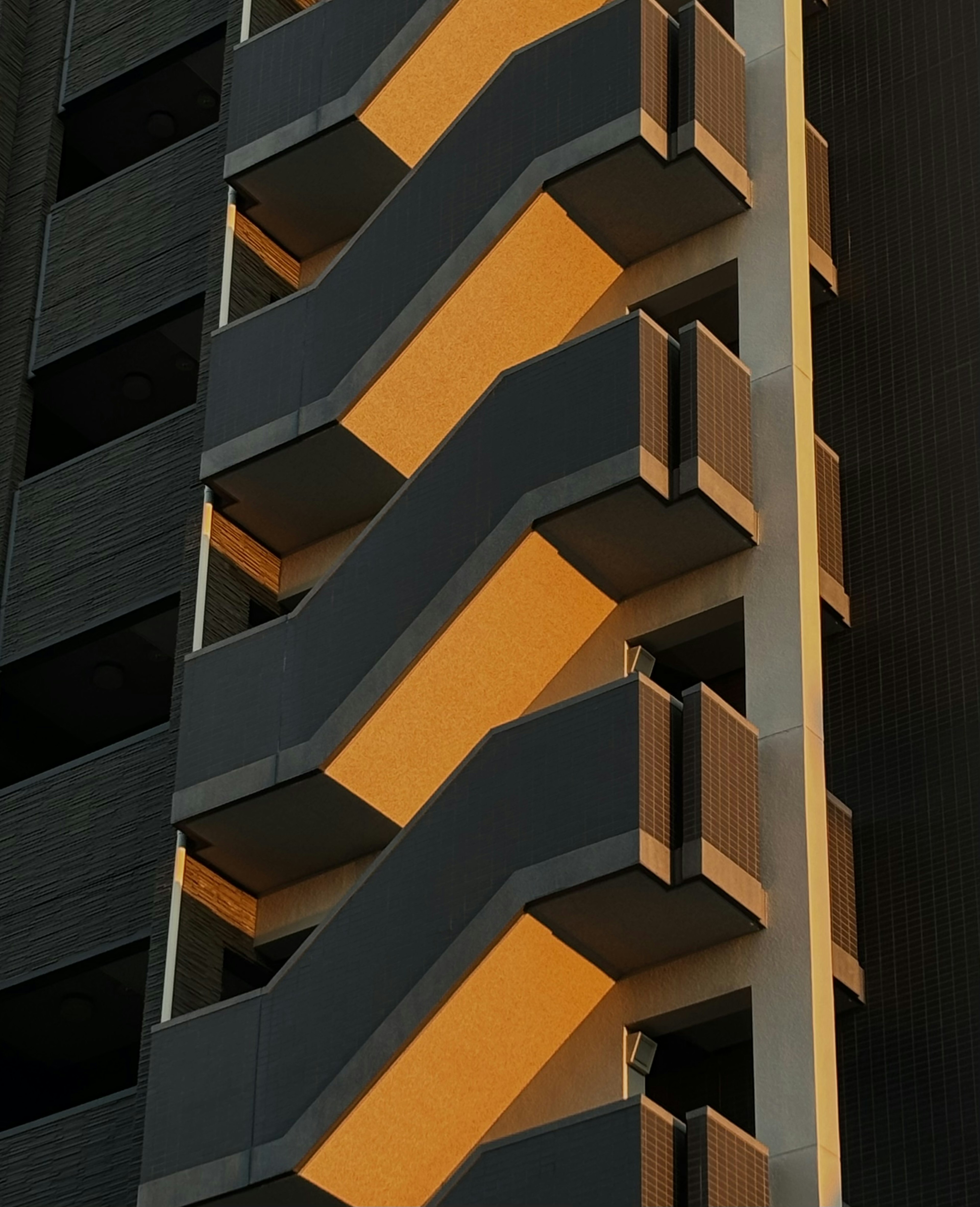 Black building exterior featuring orange and gray zigzag balconies