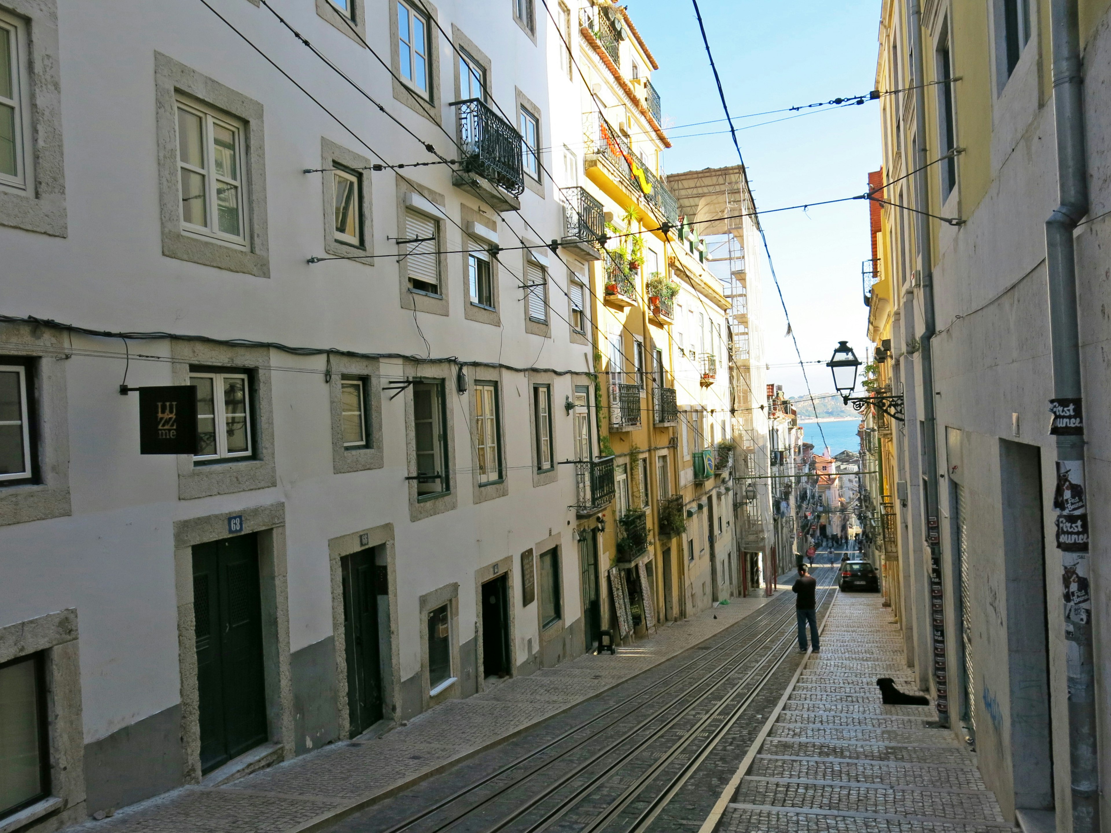 Rue étroite à Lisbonne avec des bâtiments blancs et des rails de tramway