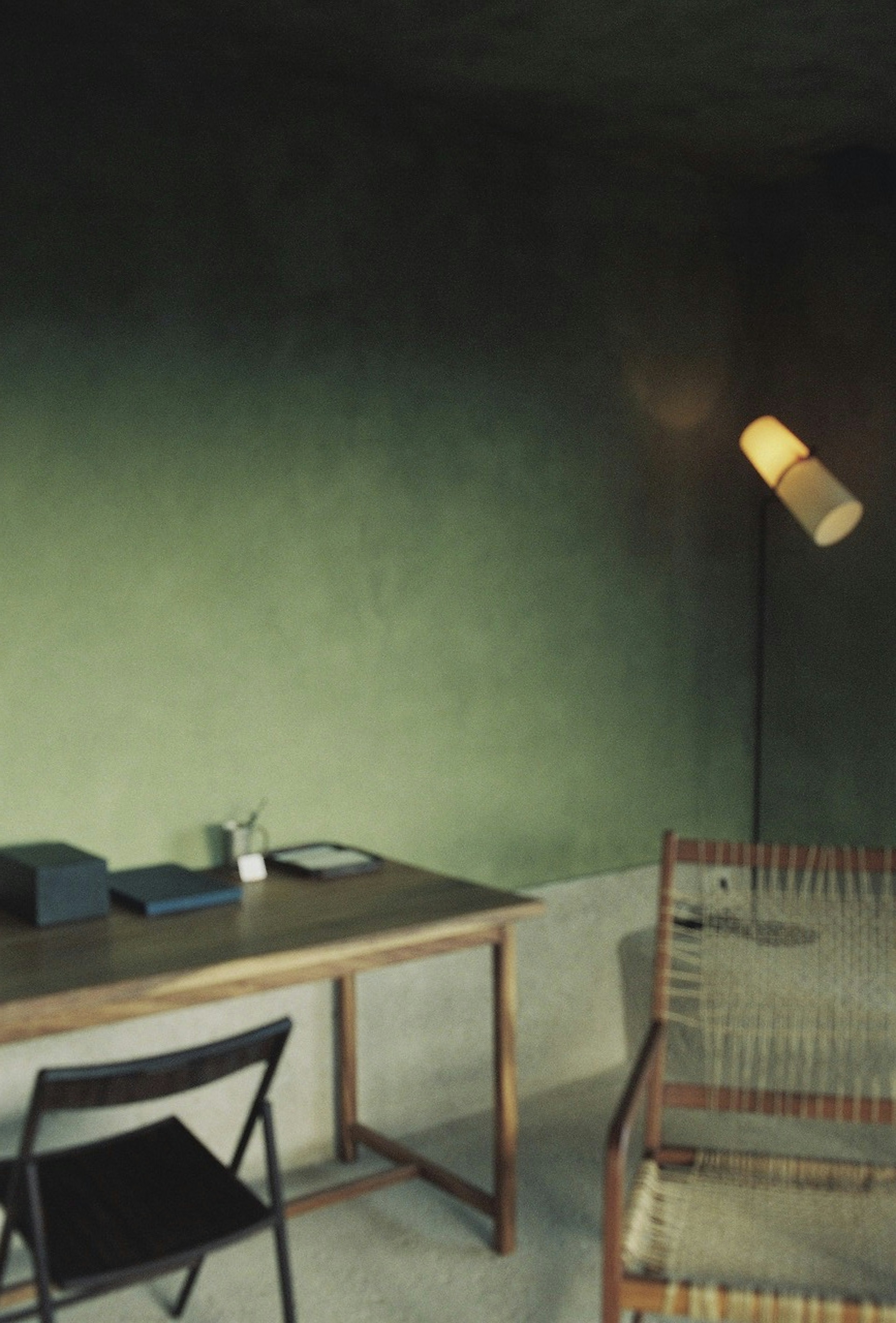 Interior with a green wall featuring a simple desk and chair