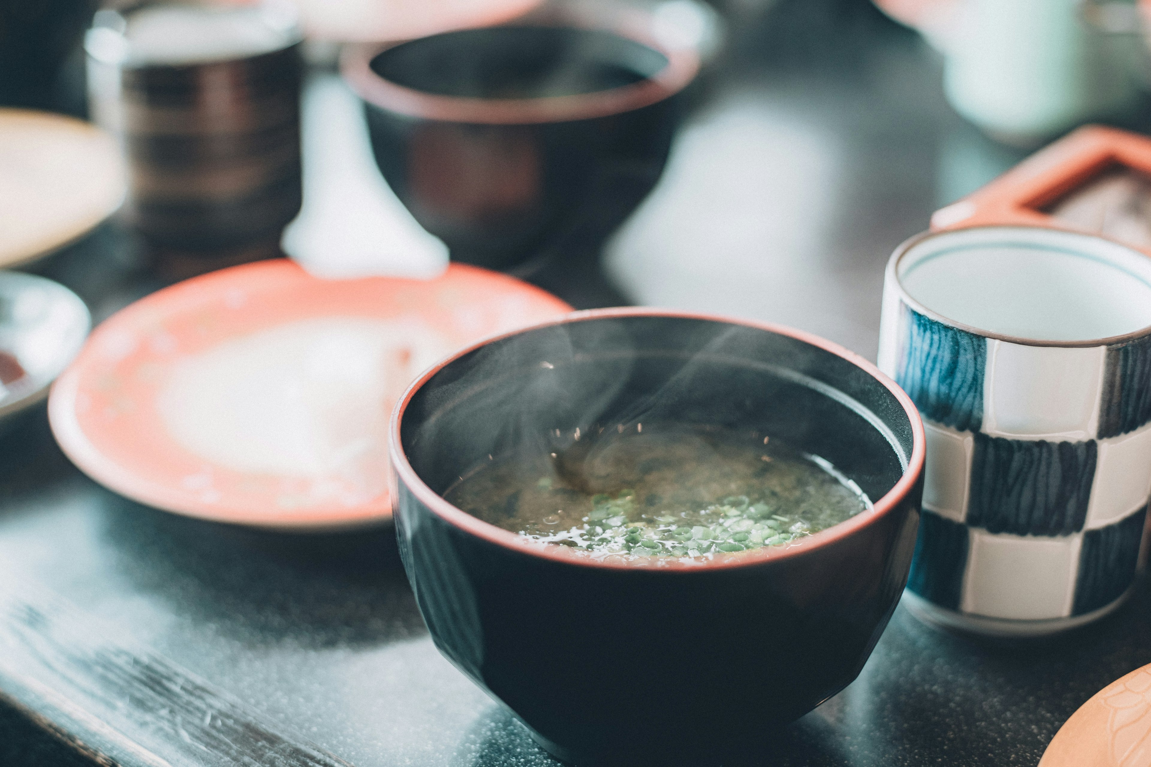 湯気の立つ黒いボウルに盛られたスープとカラフルな食器