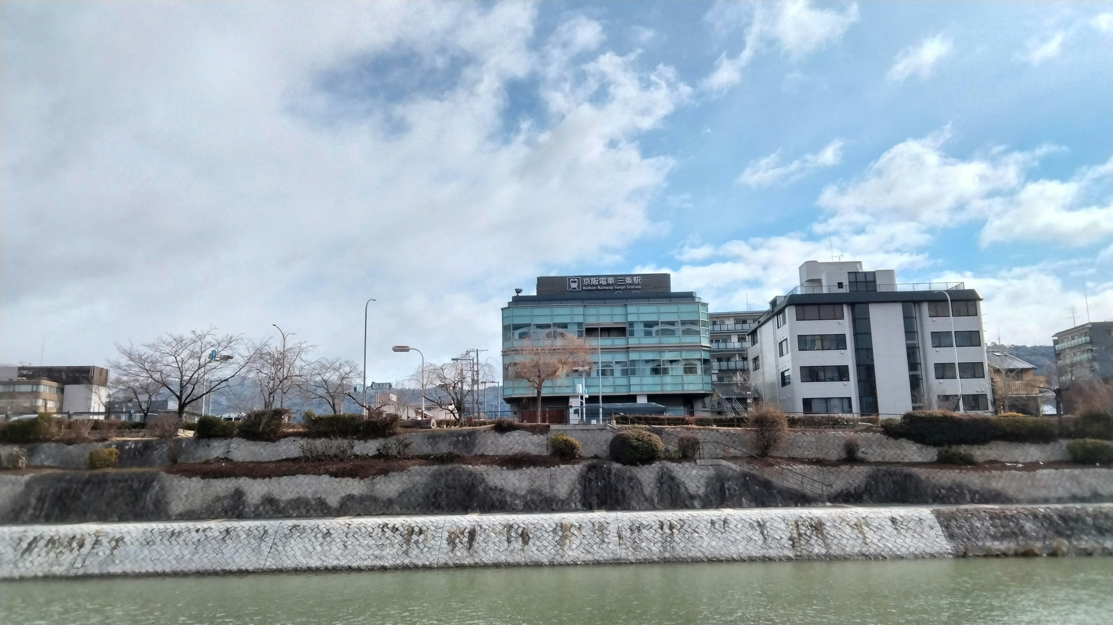 Malersicher Blick auf einen Fluss mit Gebäuden unter einem blauen Himmel und Wolken