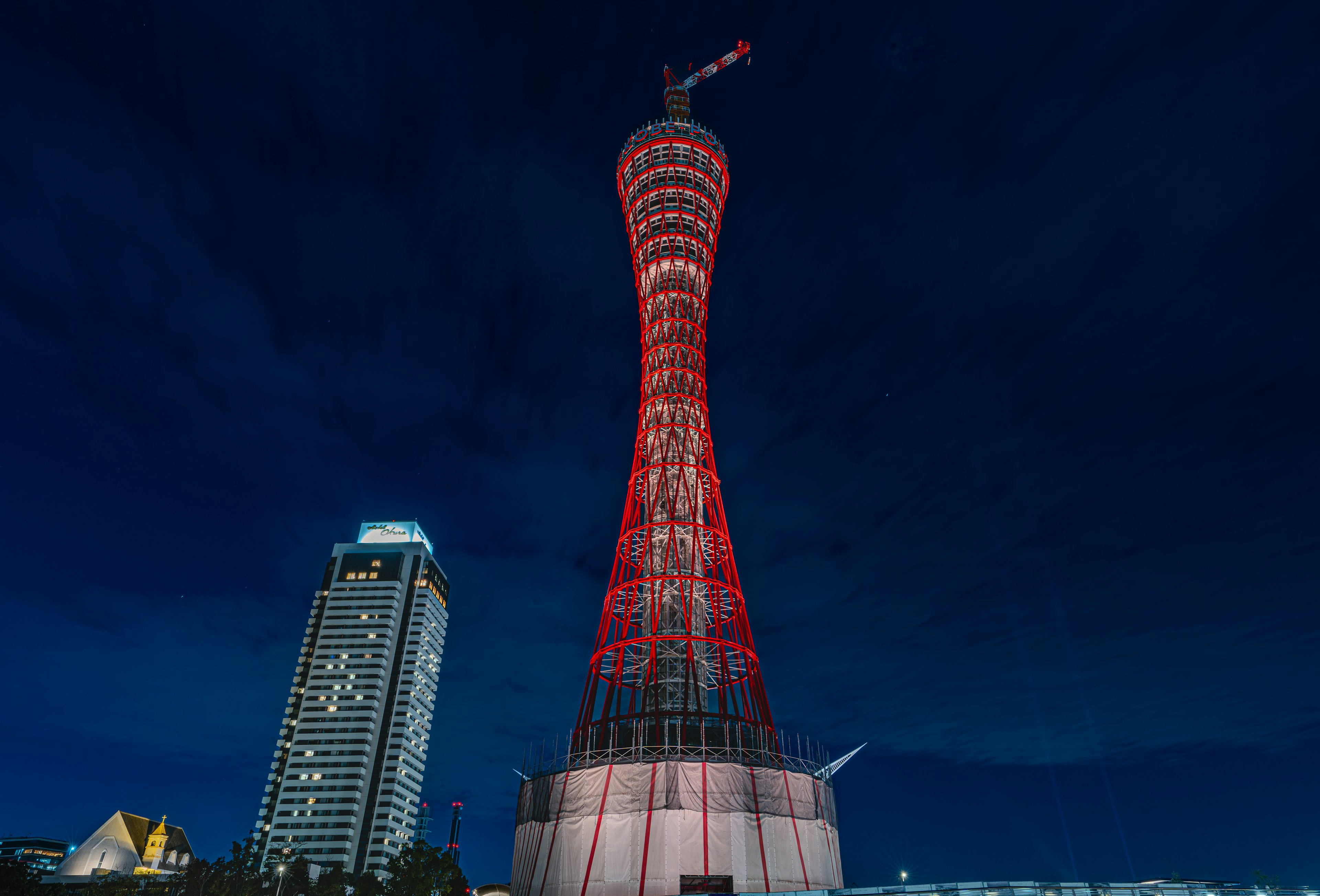 Tour du port de Kobe la nuit illuminée en rouge avec un bâtiment au premier plan