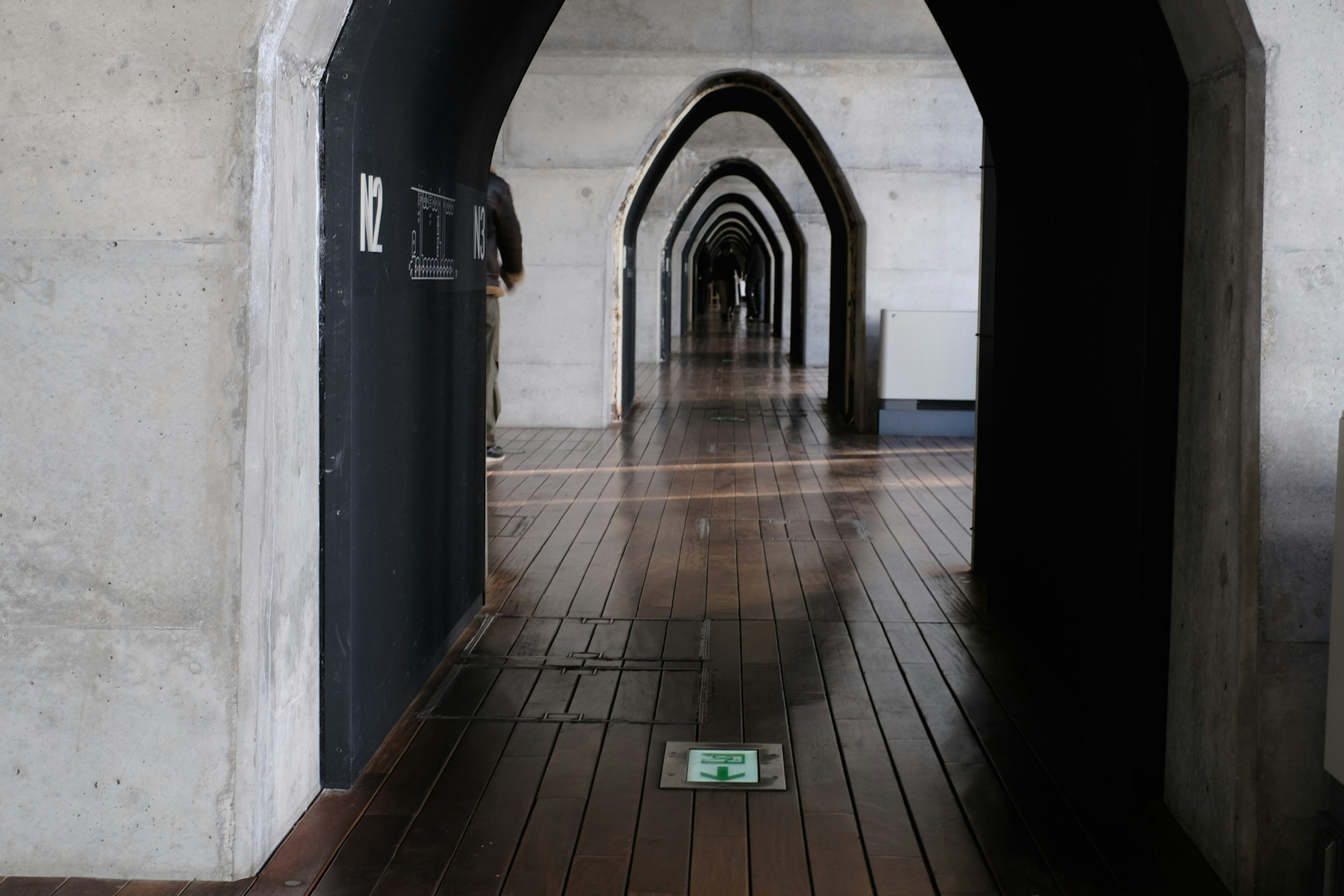 Couloir intérieur avec des arches larges et un sol en bois