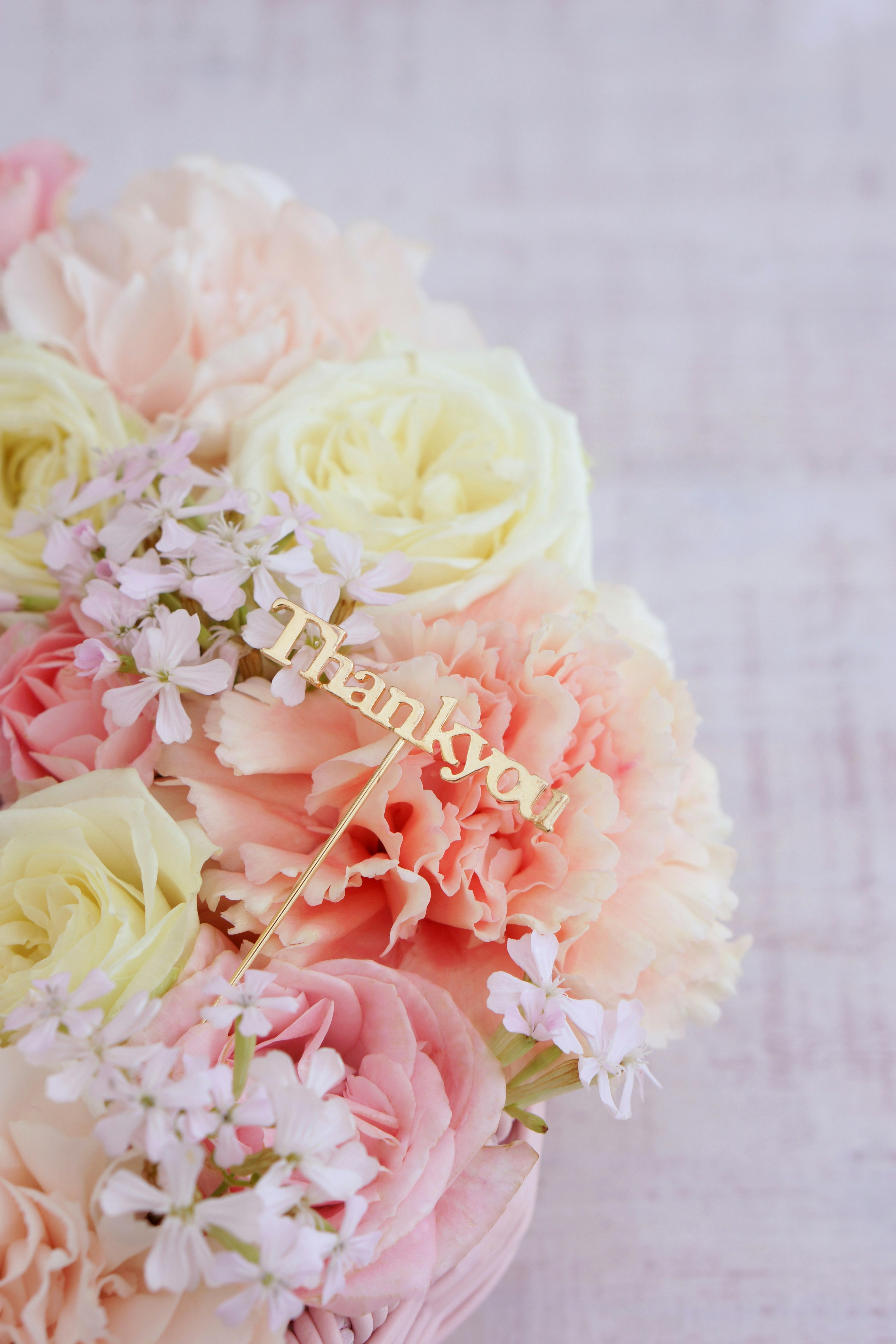 Un bouquet di fiori dai colori tenui con un messaggio di Grazie