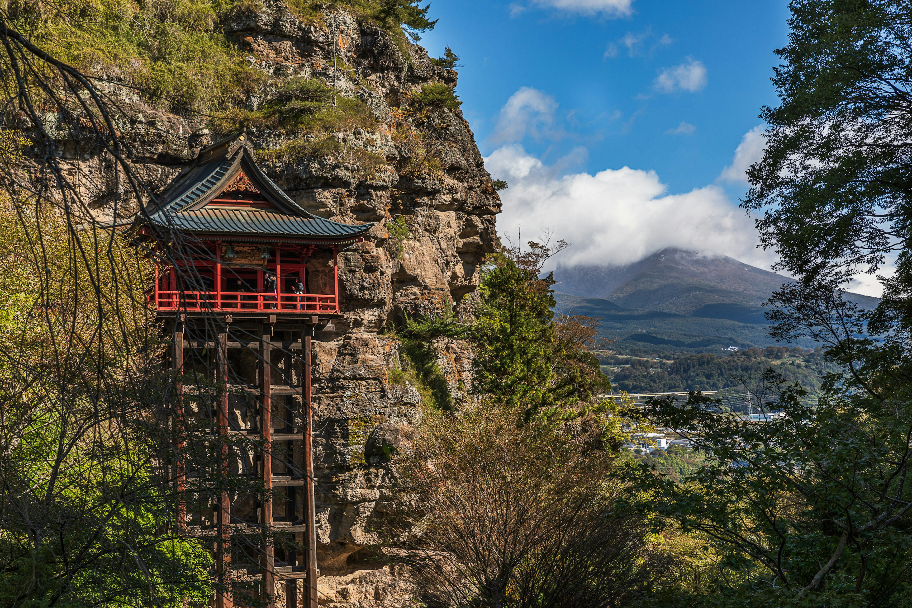 山の中腹にある赤い神社の建物と青空の背景