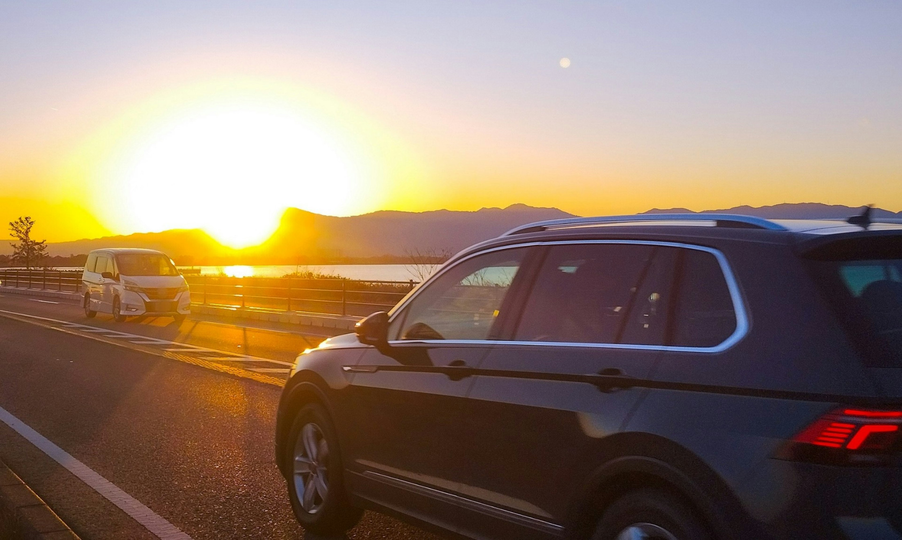 Eine malerische Ansicht von Autos auf einer Straße mit Sonnenuntergang im Hintergrund