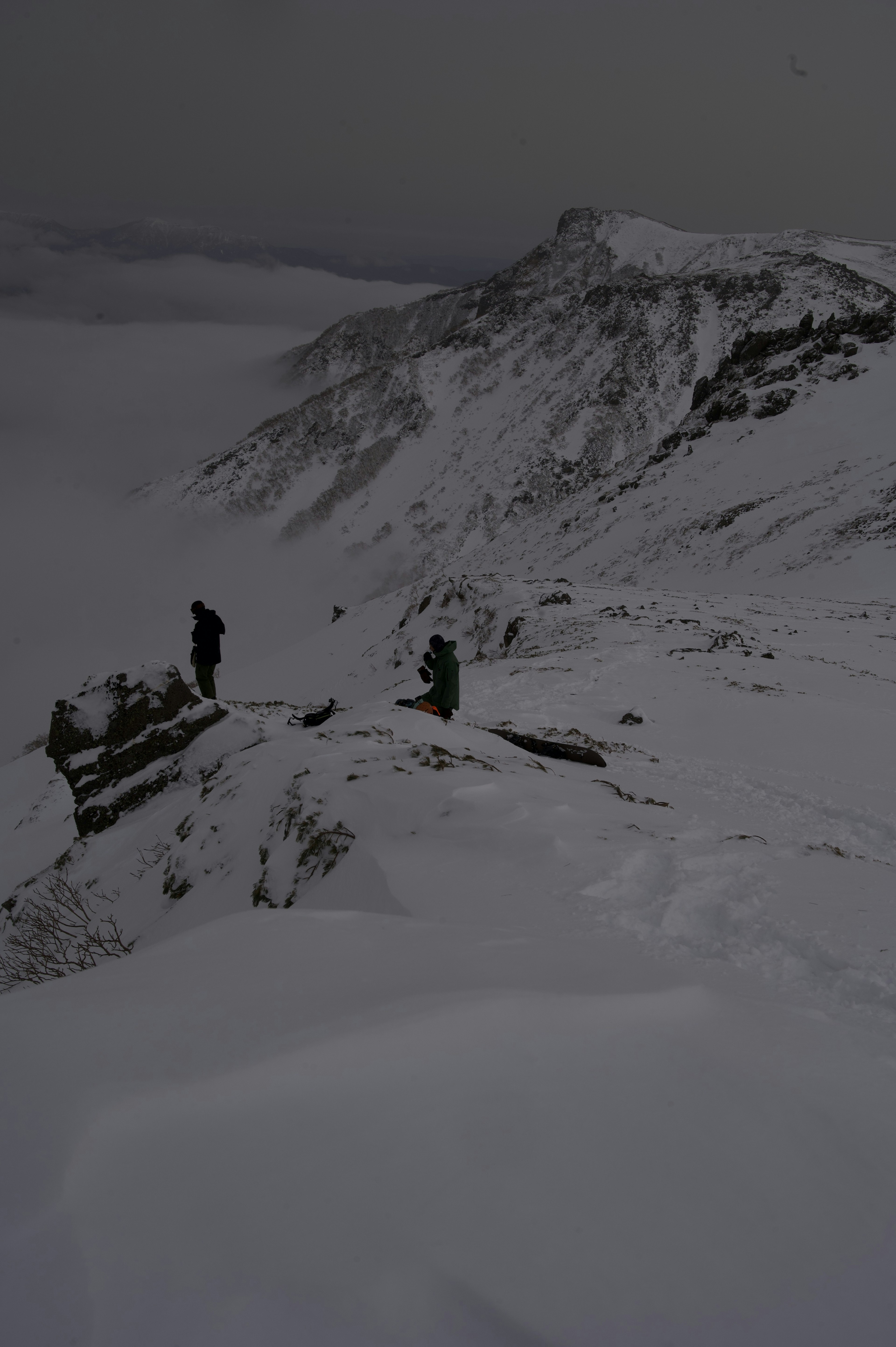 Dos escaladores de pie en la cima de una montaña cubierta de nieve