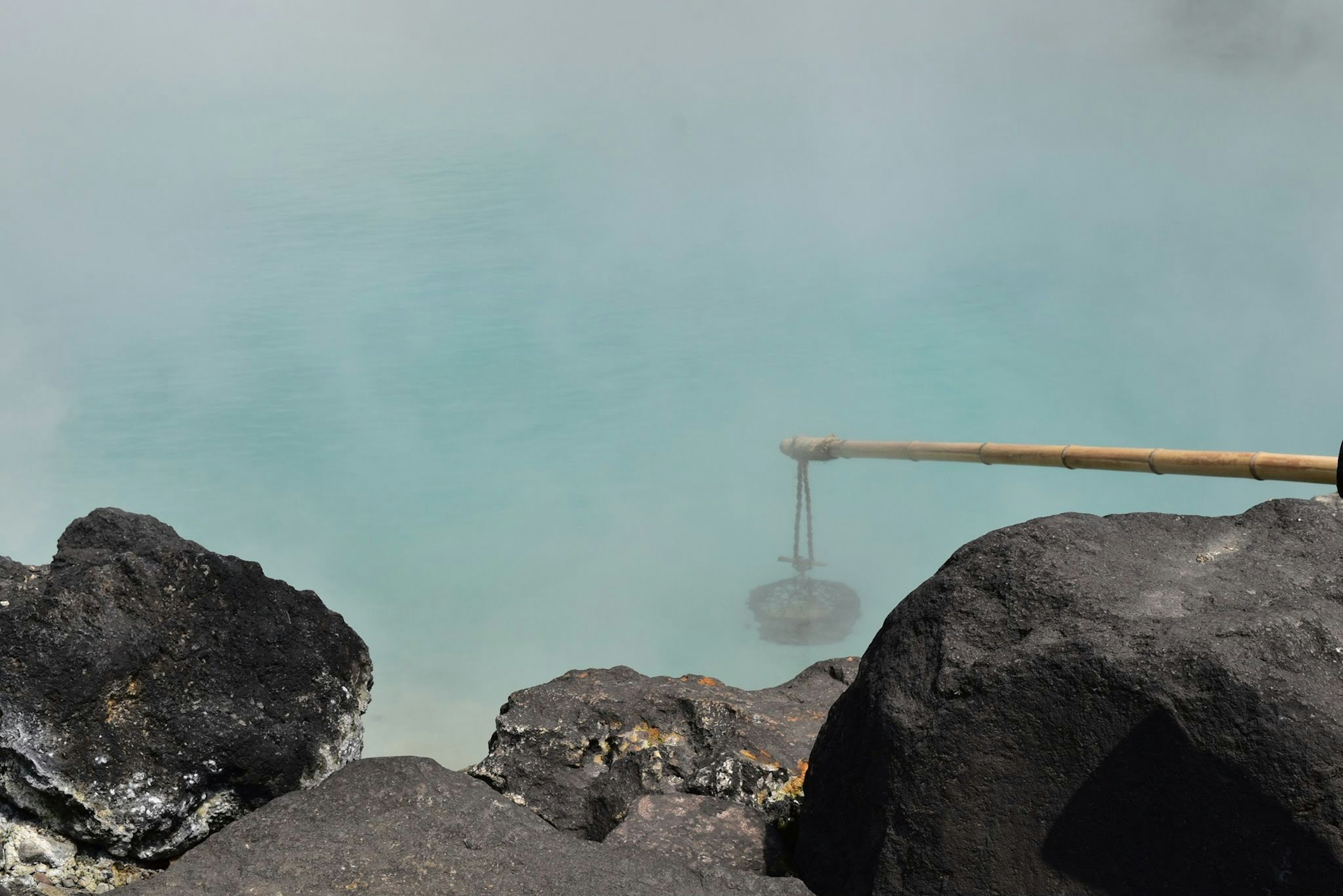 Pemandangan sumber panas biru dikelilingi batu