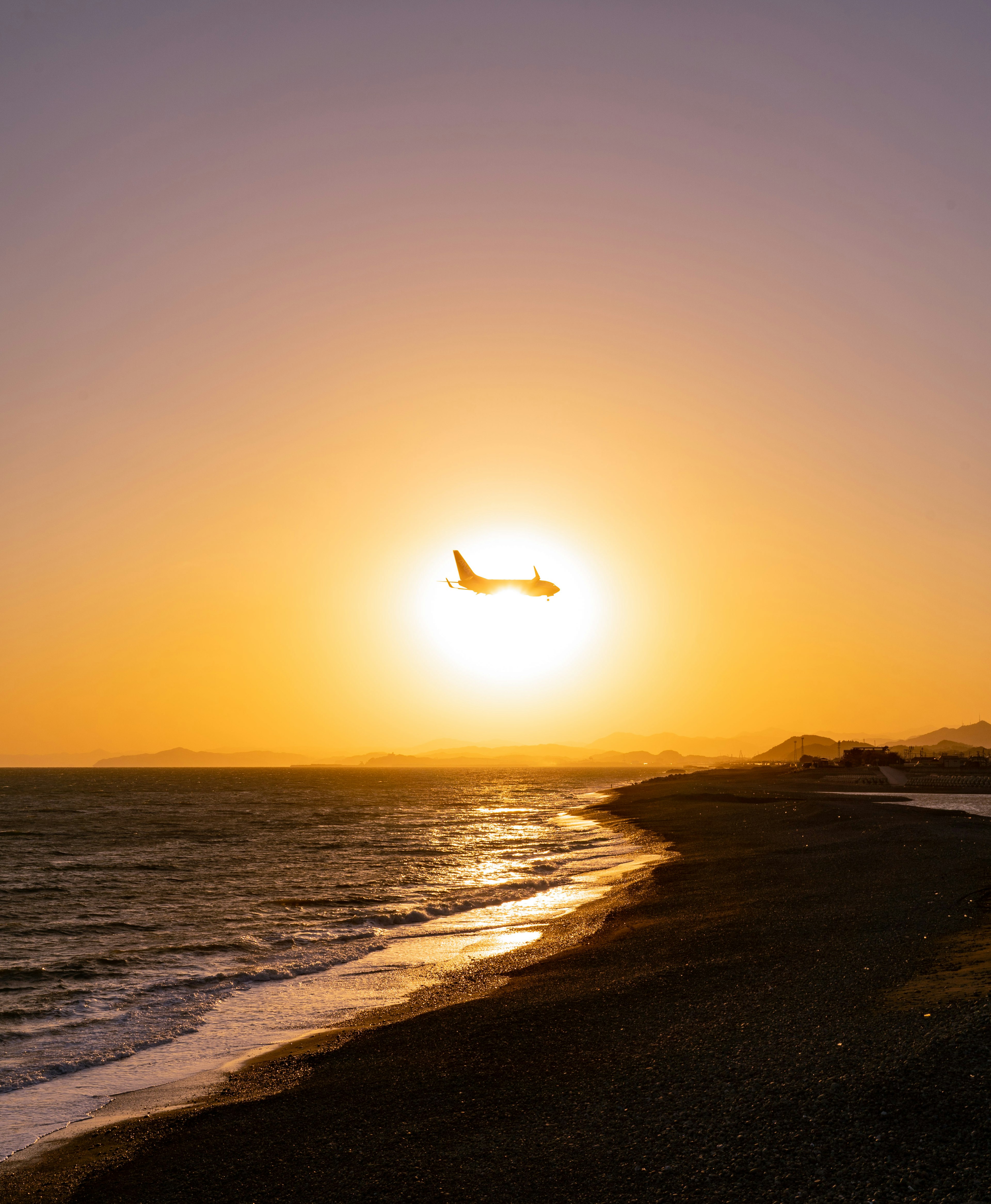 夕日を背景に飛行機が海の上を飛んでいる風景