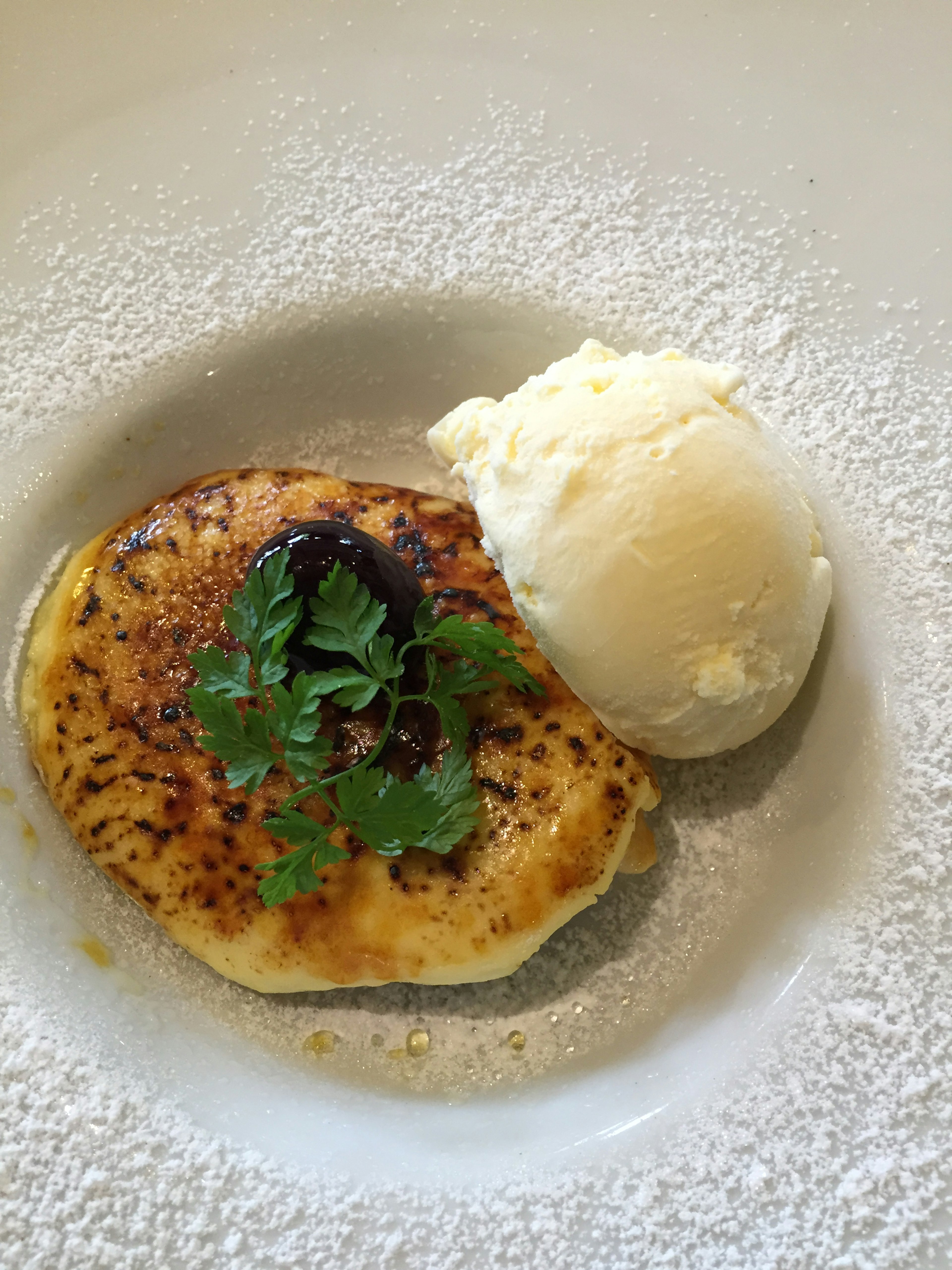 Golden pancake topped with ice cream and fresh cilantro