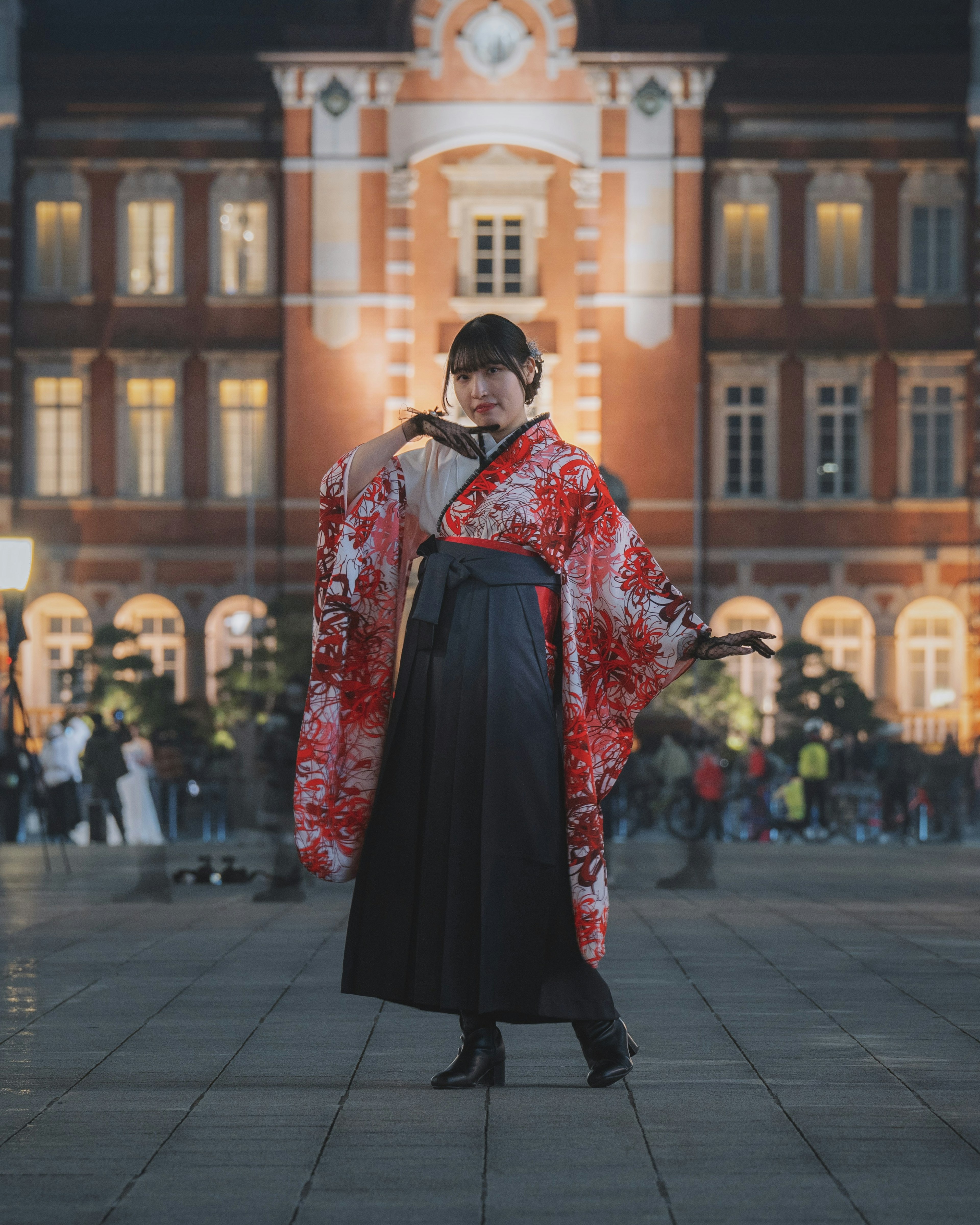 夜の東京駅で華やかな着物を着た女性がポーズを取っている