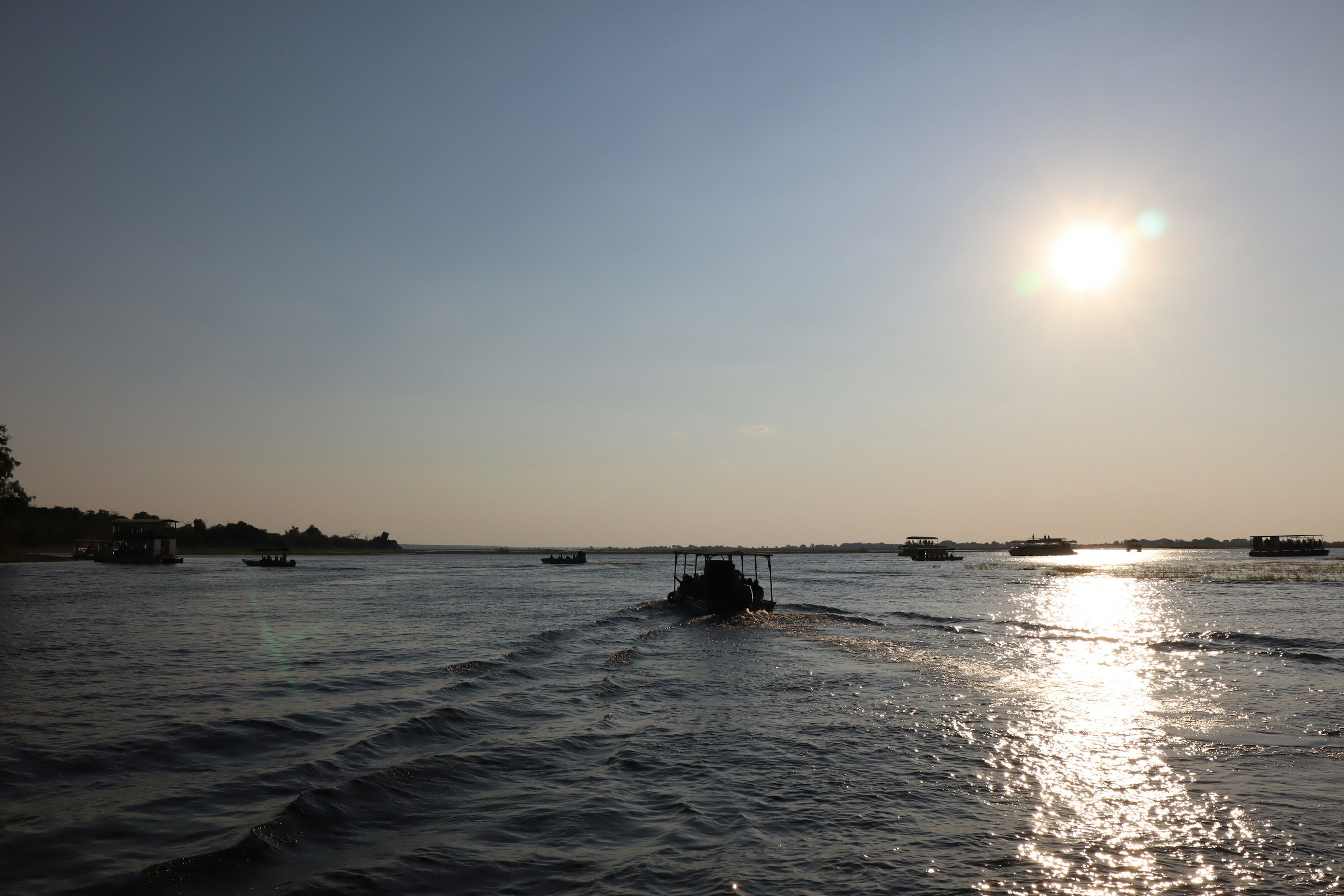 Ruhige Sonnenuntergangsszene mit Booten auf dem Wasser, die Sonnenlicht reflektieren