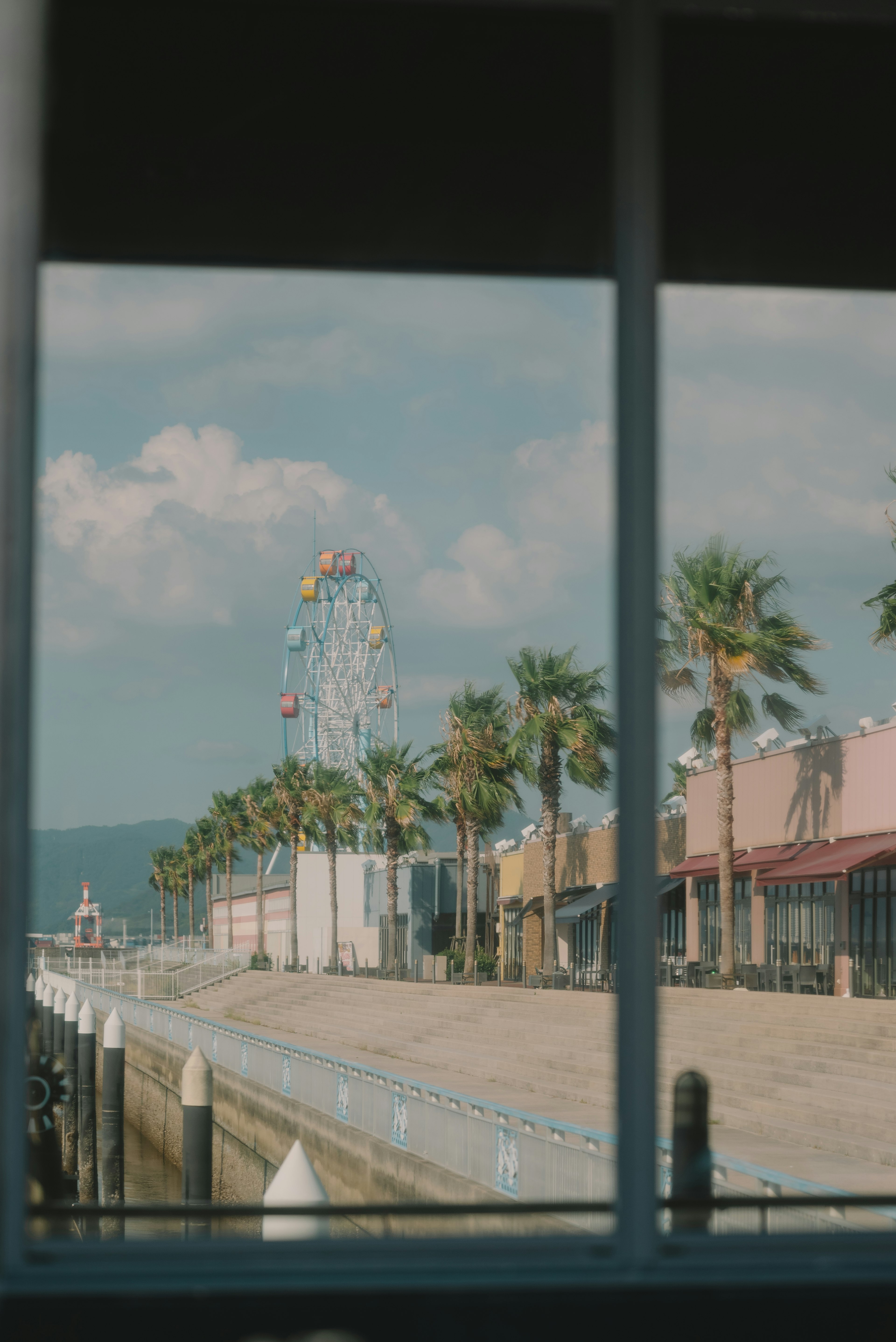 Blick auf ein Riesenrad und Palmen durch ein Fenster