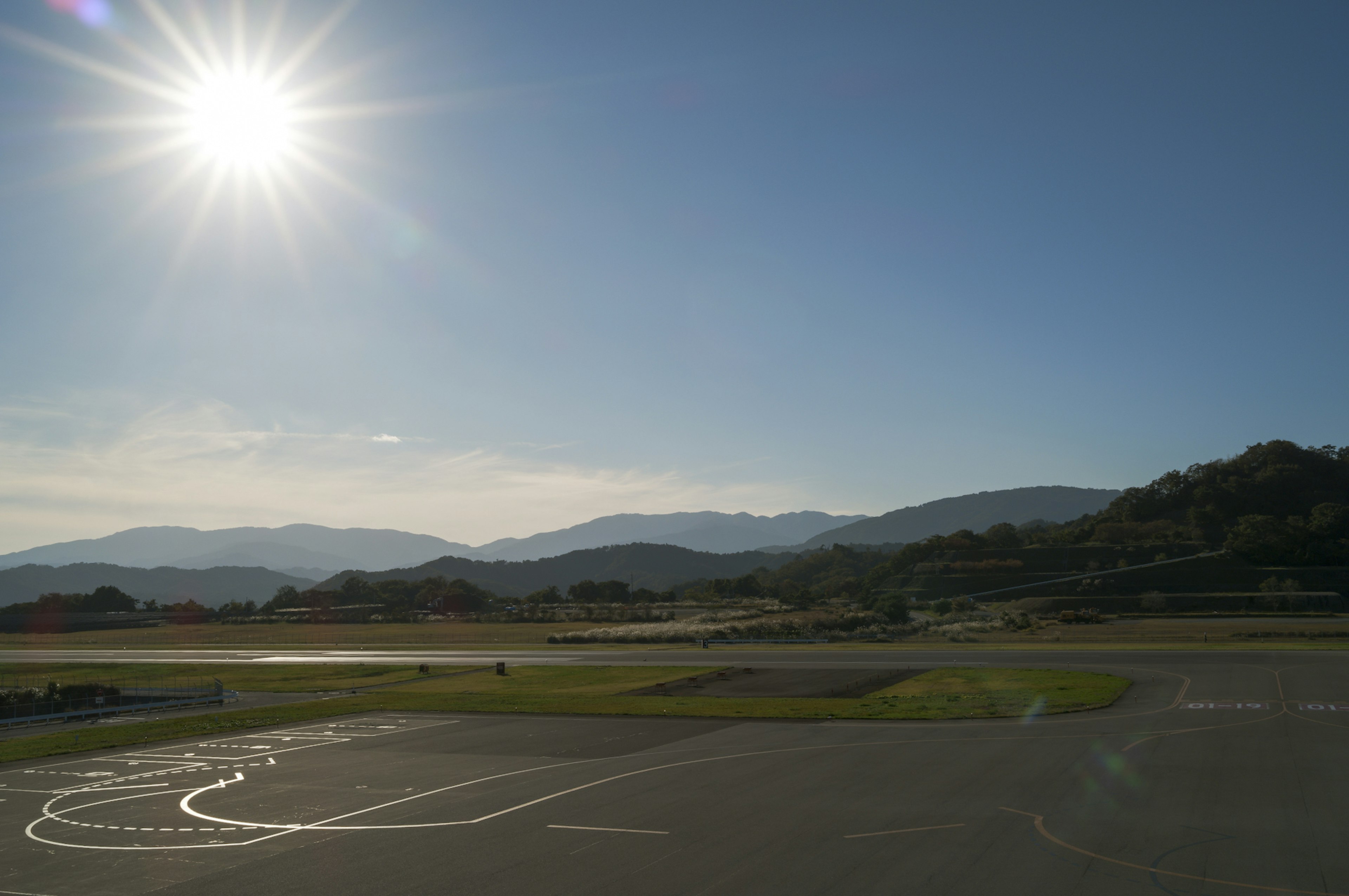 晴れた空と太陽が輝く風景の写真 山々と滑走路が見える