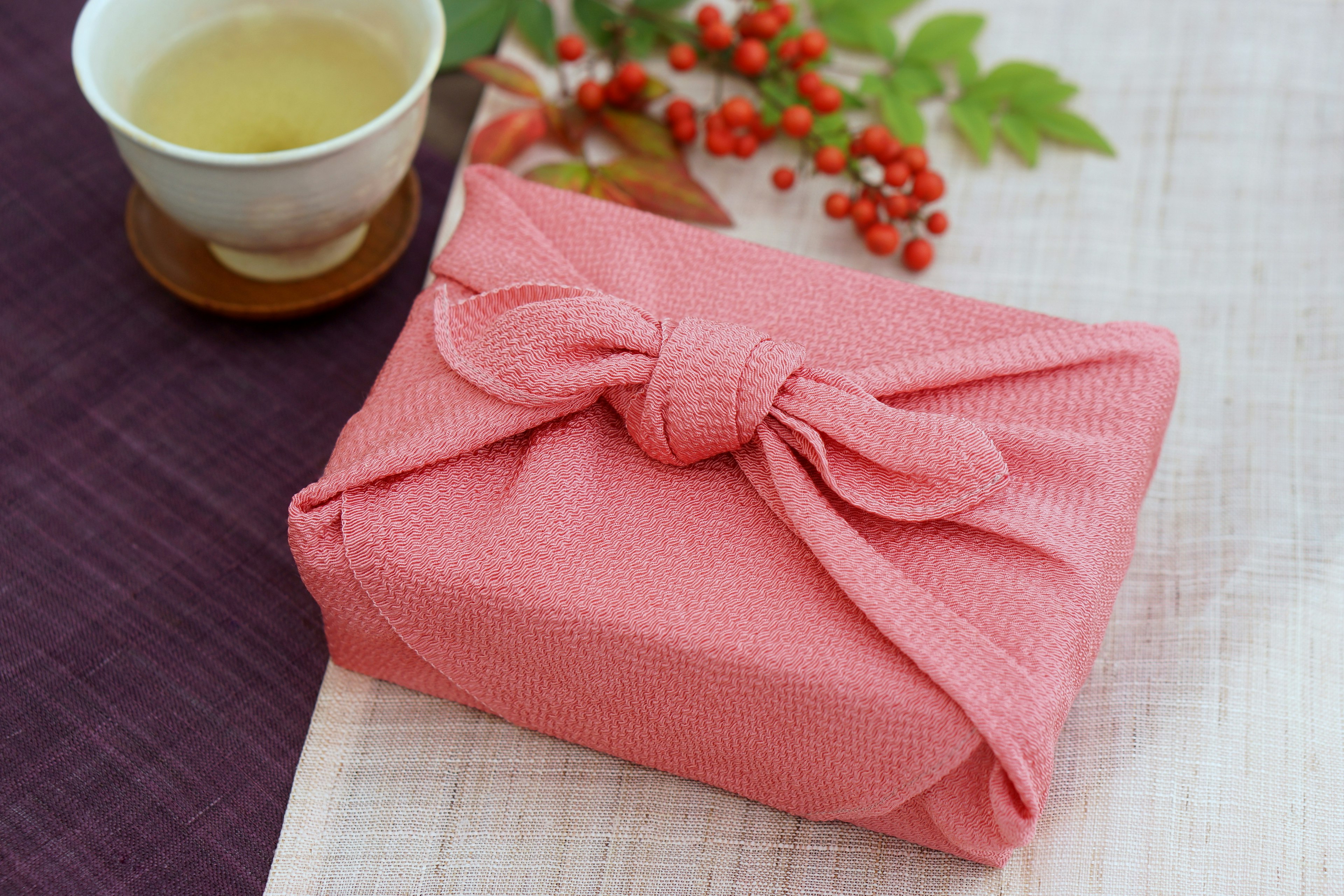 A pink fabric-wrapped gift with a tea cup on a table setting