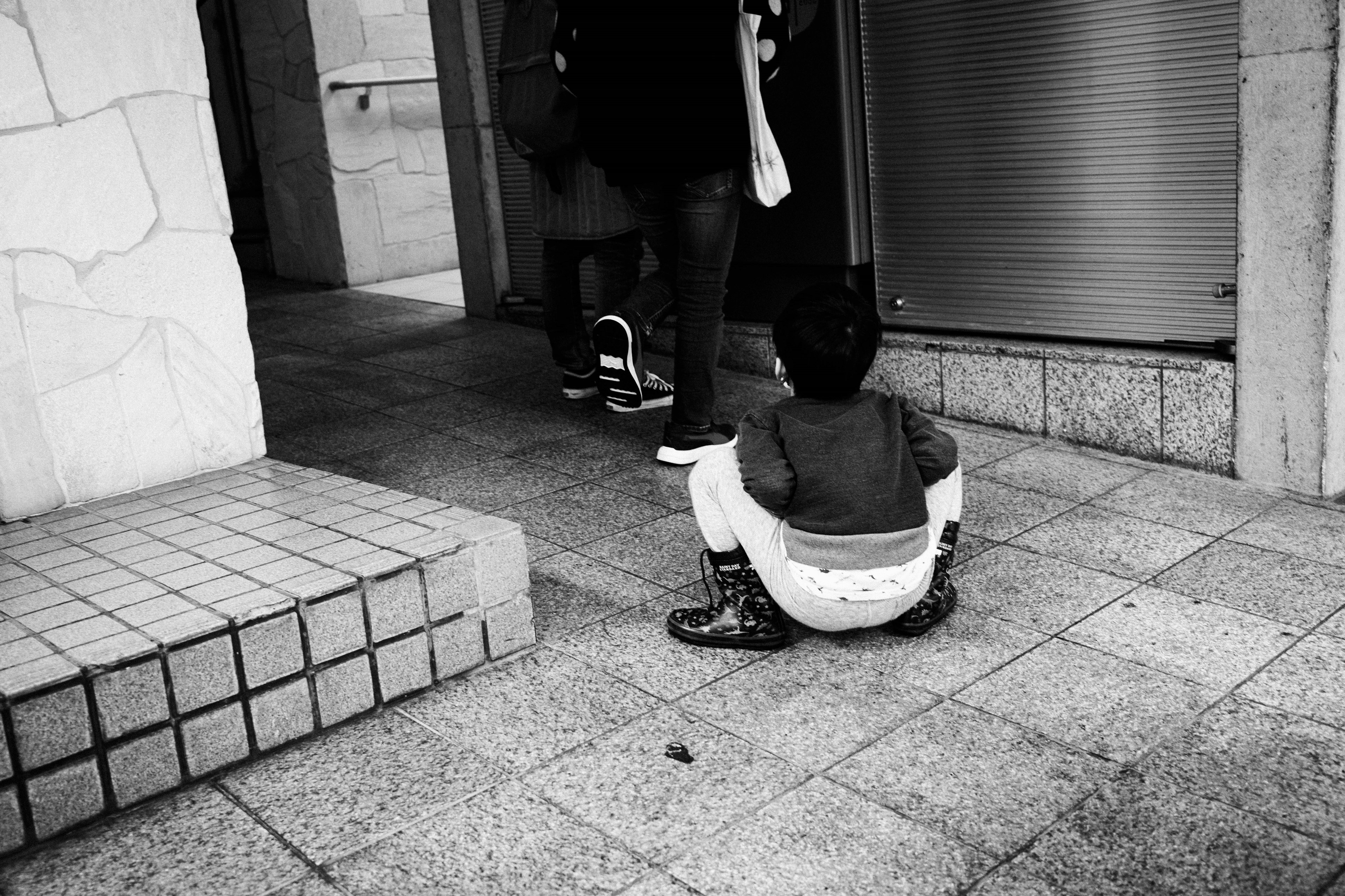 Foto in bianco e nero di un bambino seduto per terra all'aperto