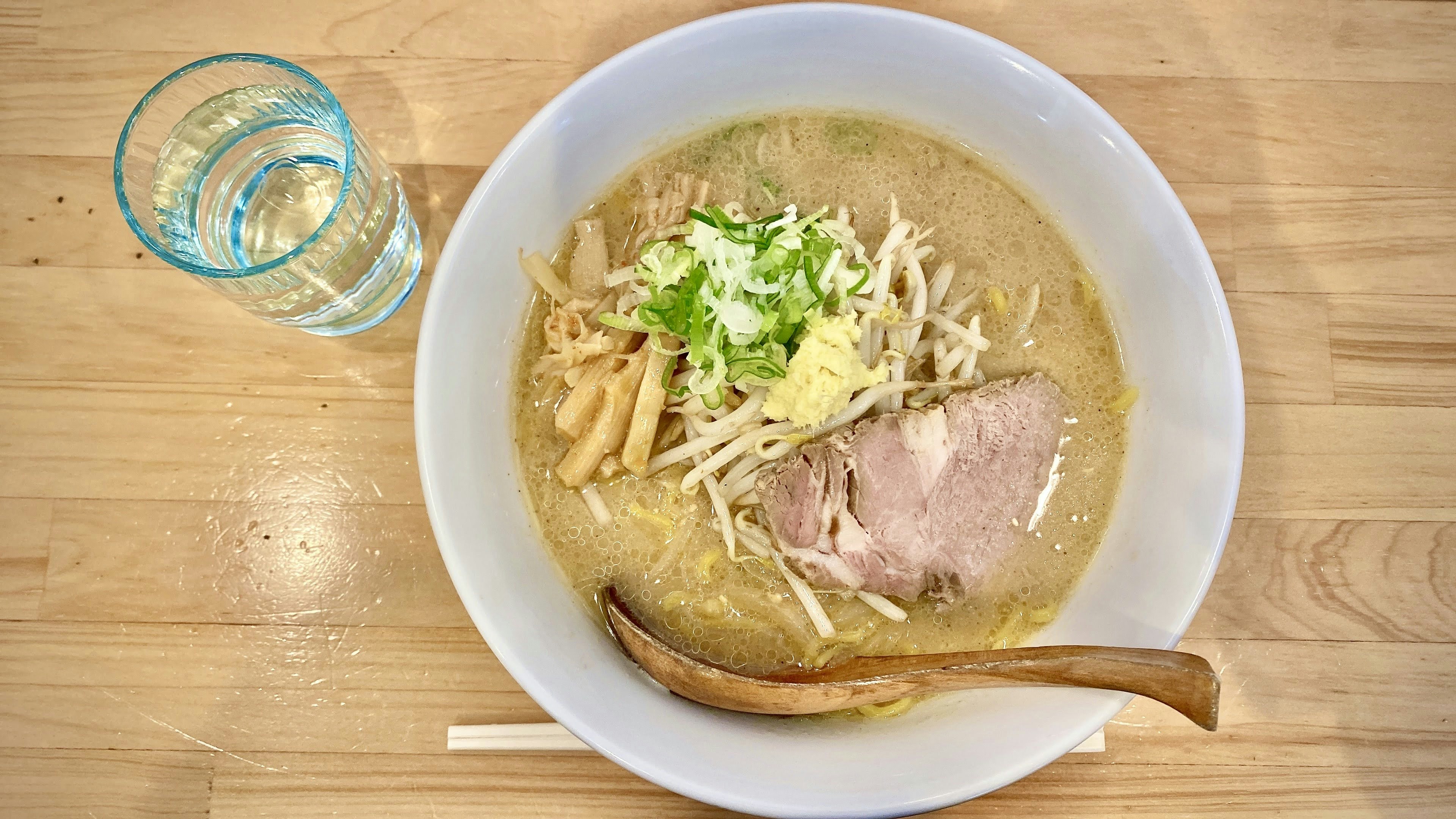 ラーメンのボウルにチャーシューと野菜がトッピングされた料理