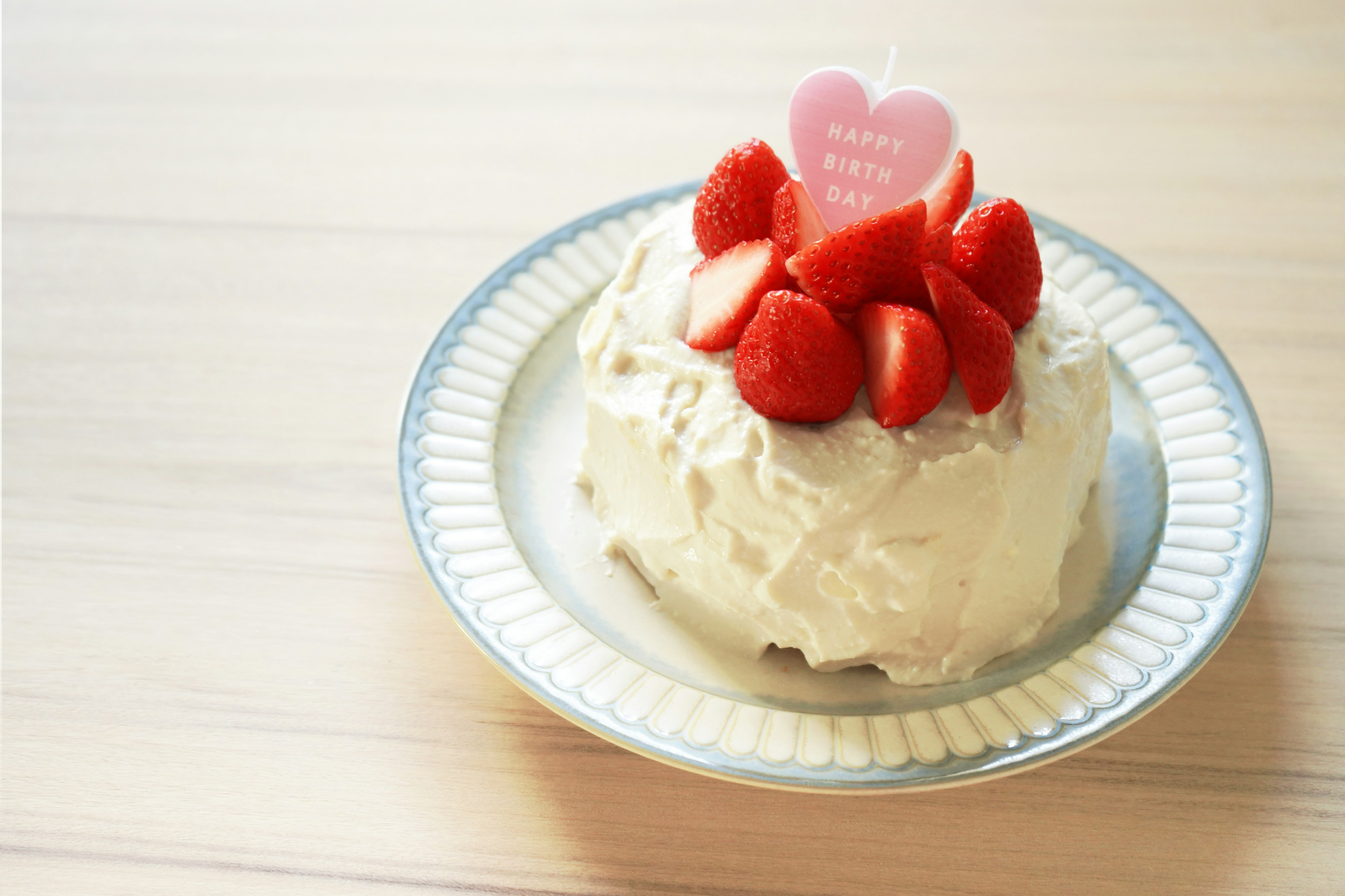 Kue krim yang dihiasi dengan stroberi dan topper berbentuk hati