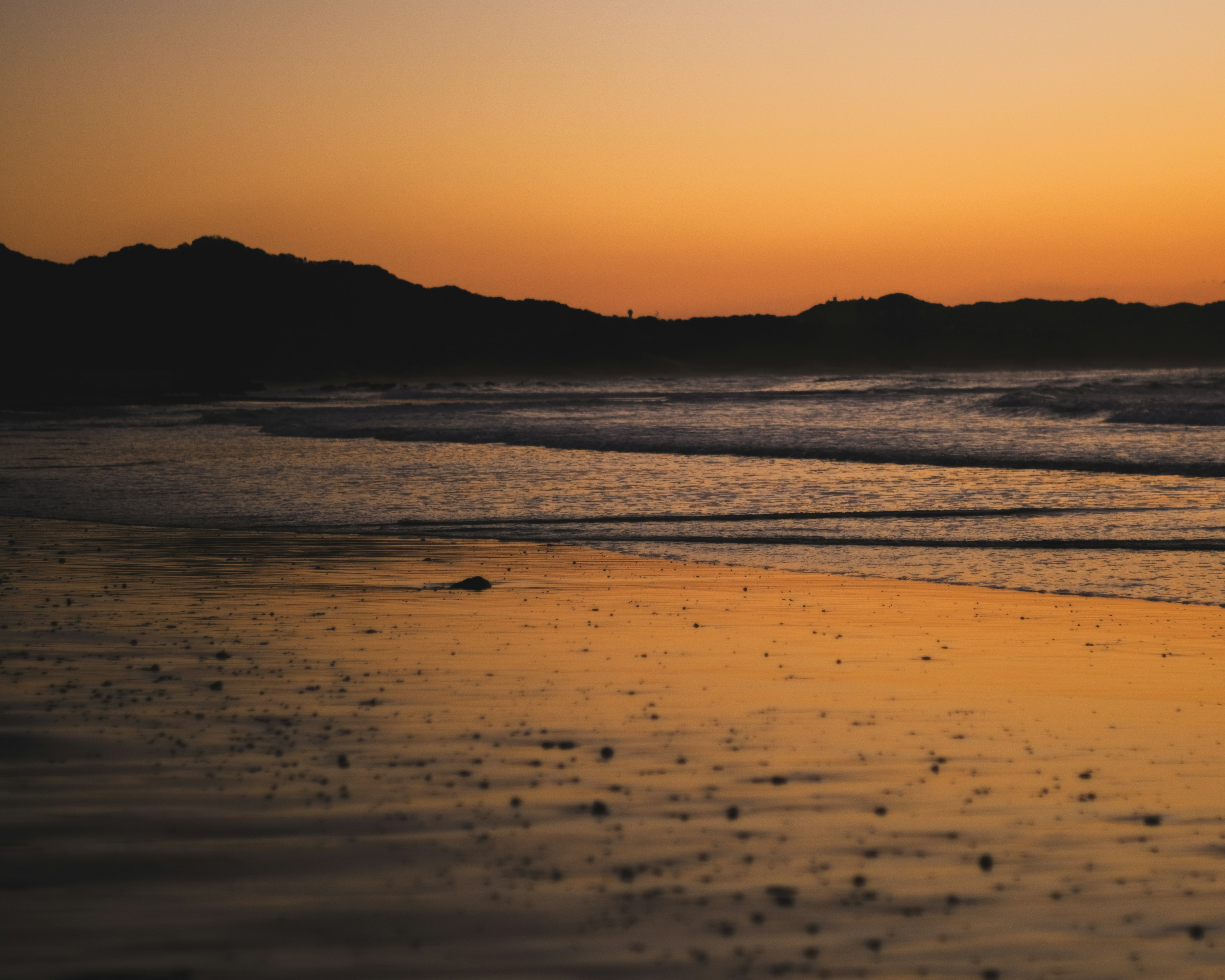 Vue de plage sereine avec le coucher de soleil se reflétant sur l'eau