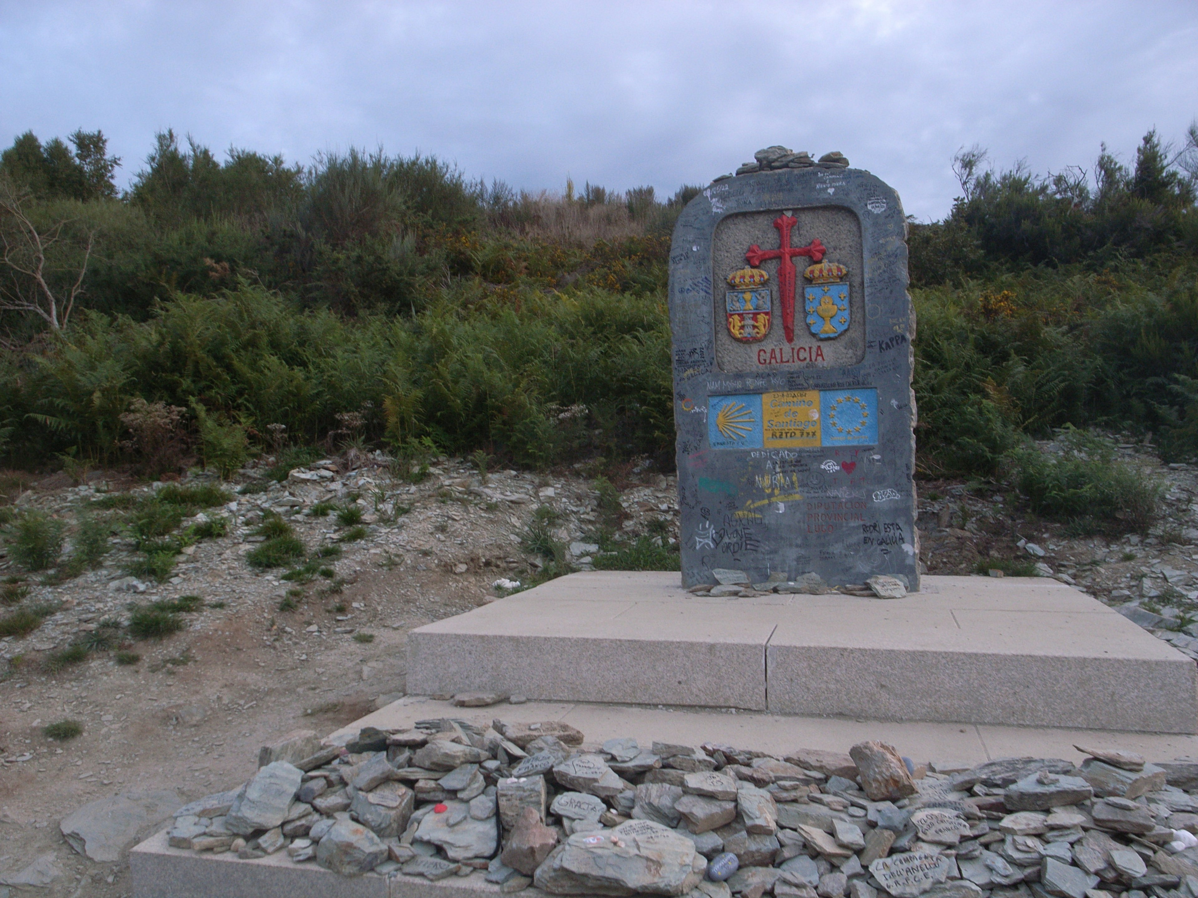 Ein Steindenkmal mit einem bunten Wappen vor einer natürlichen Kulisse