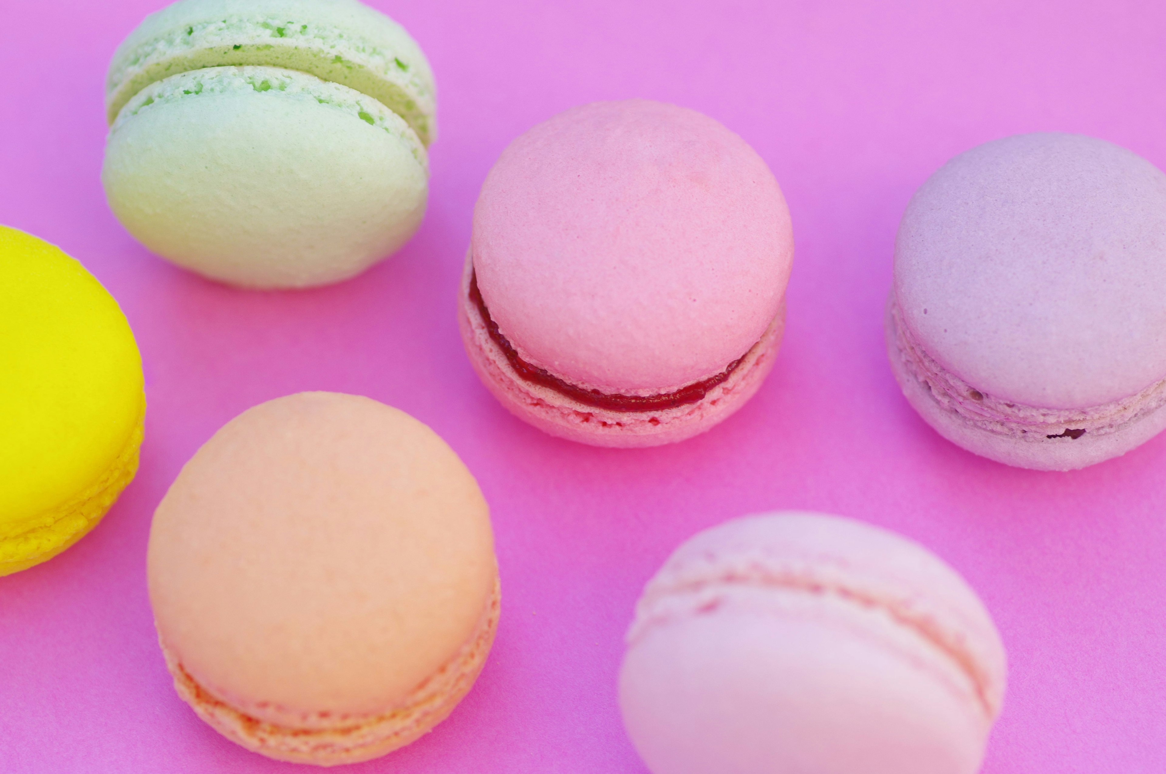 Macarons colorés disposés sur un fond rose