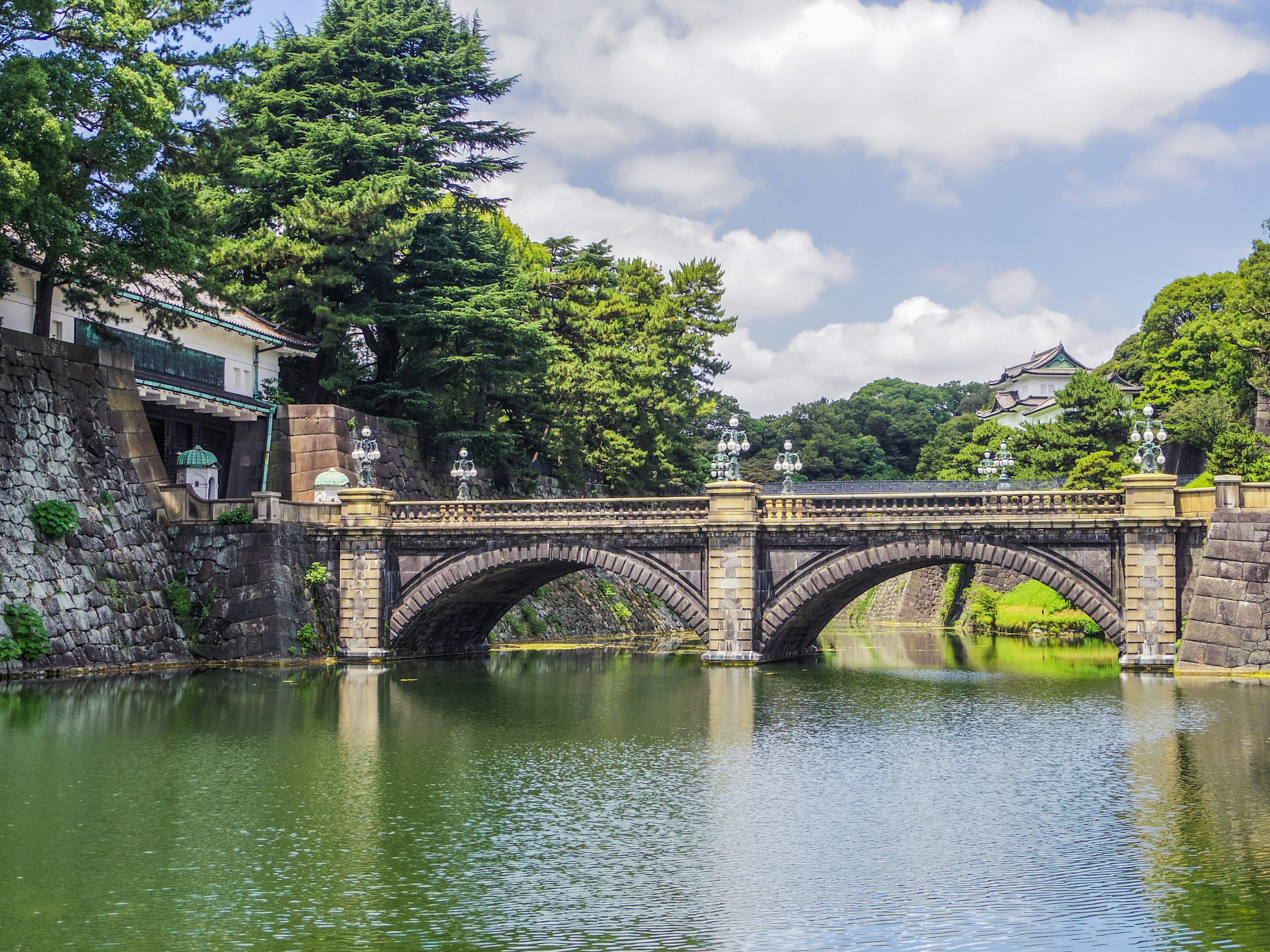 A beautiful stone bridge spans a pond reflecting the surrounding greenery