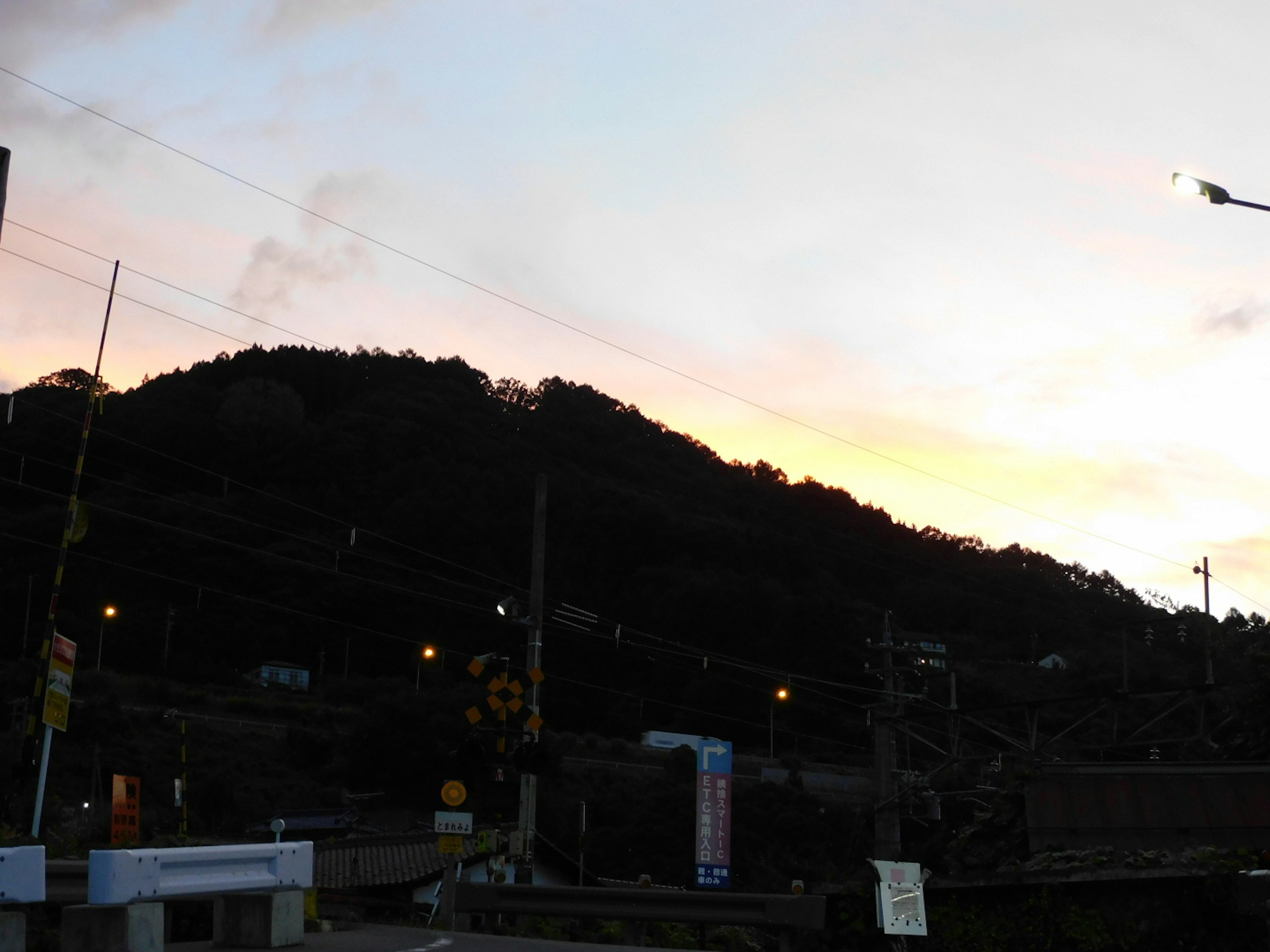 Silhouette eines Hügels gegen einen Sonnenuntergang mit Straßenlaternen