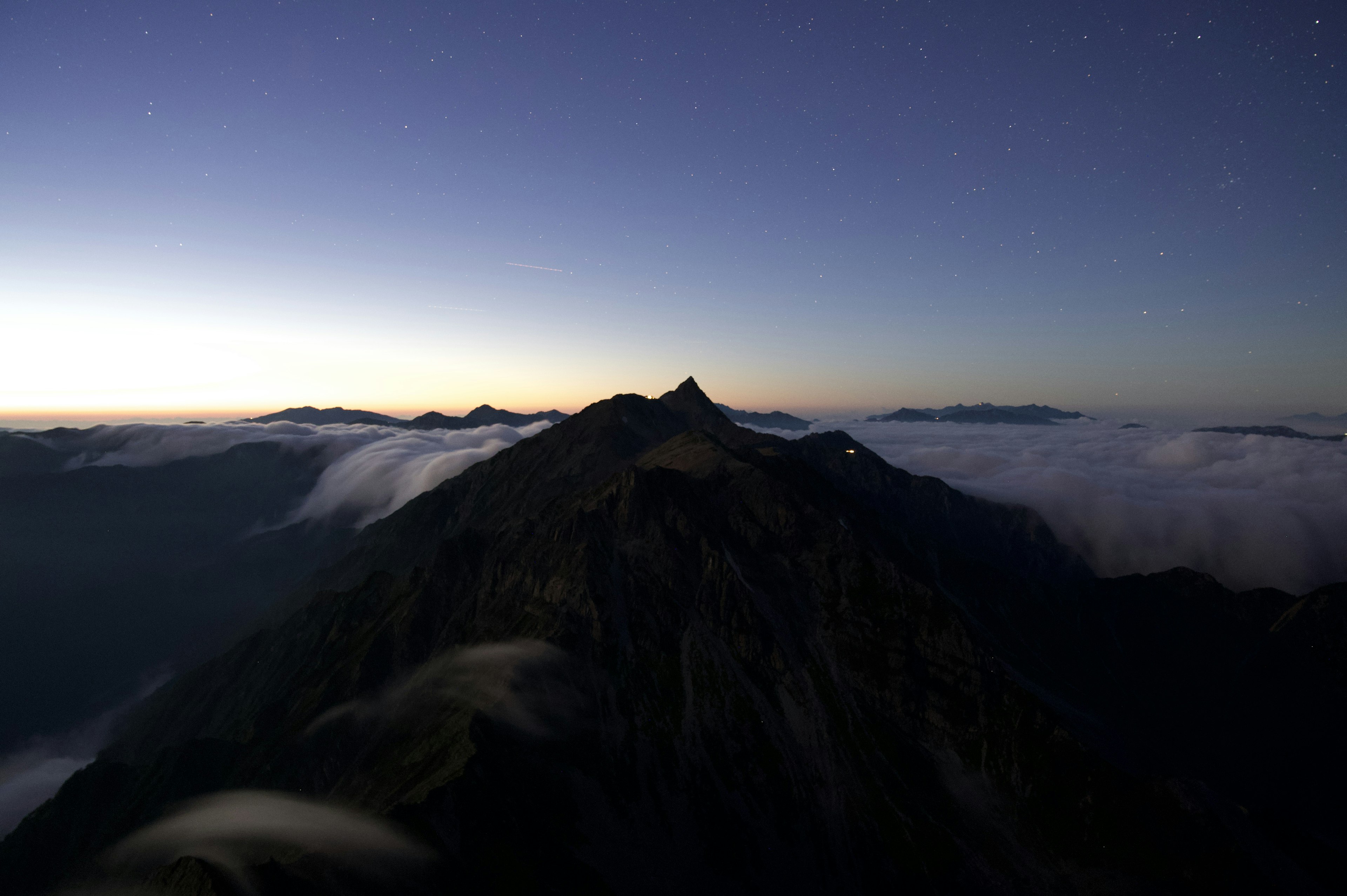 Punta di montagna circondata da nuvole all'alba