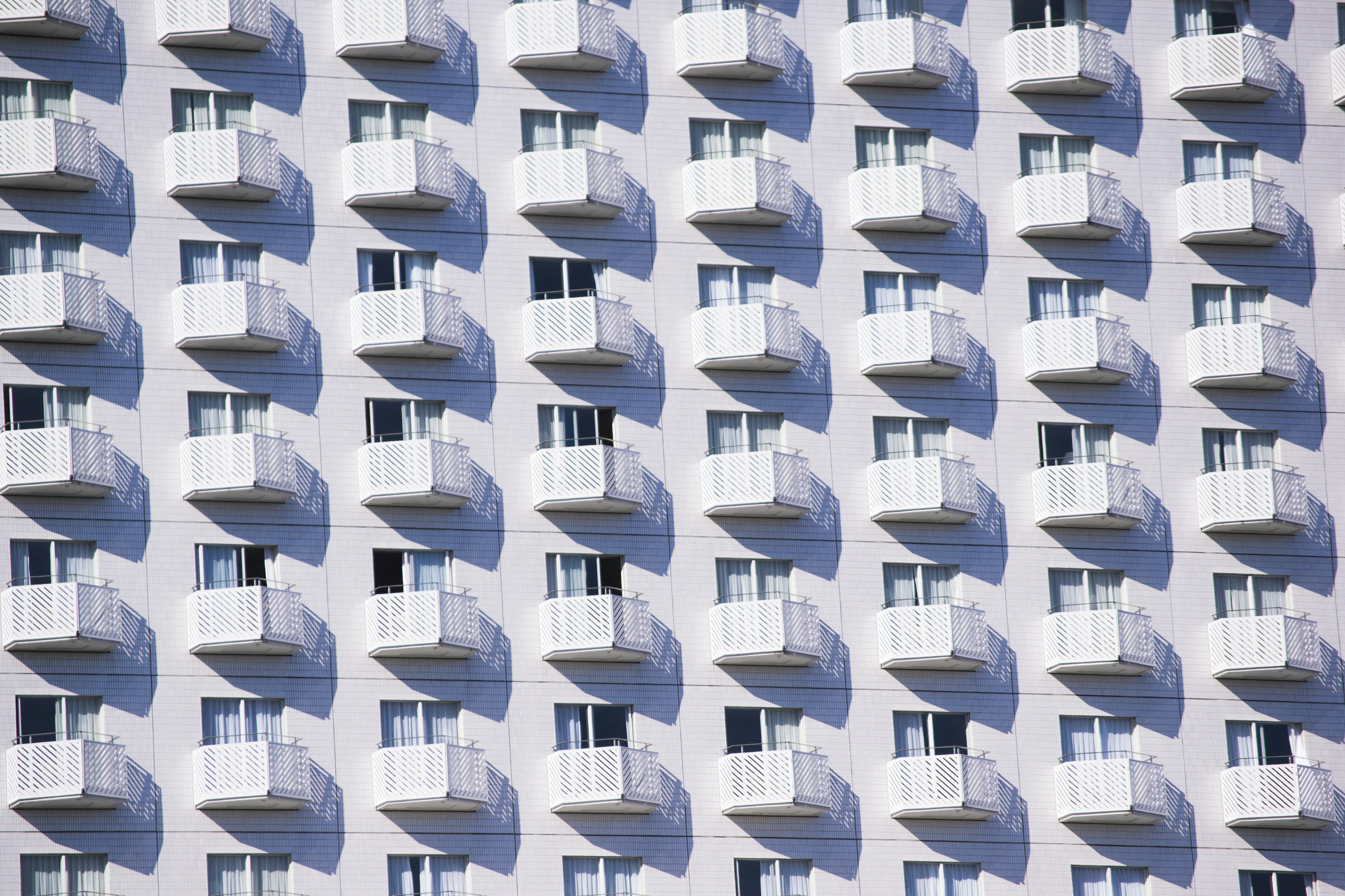 Exterior of a building featuring rows of balconies against a white wall