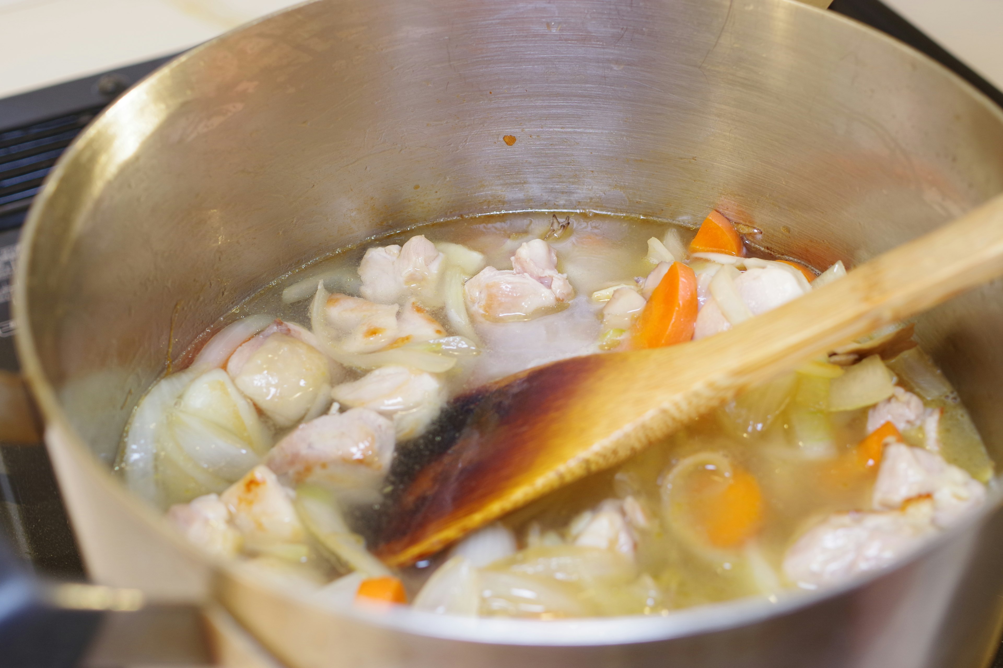 A pot simmering with chicken and vegetables