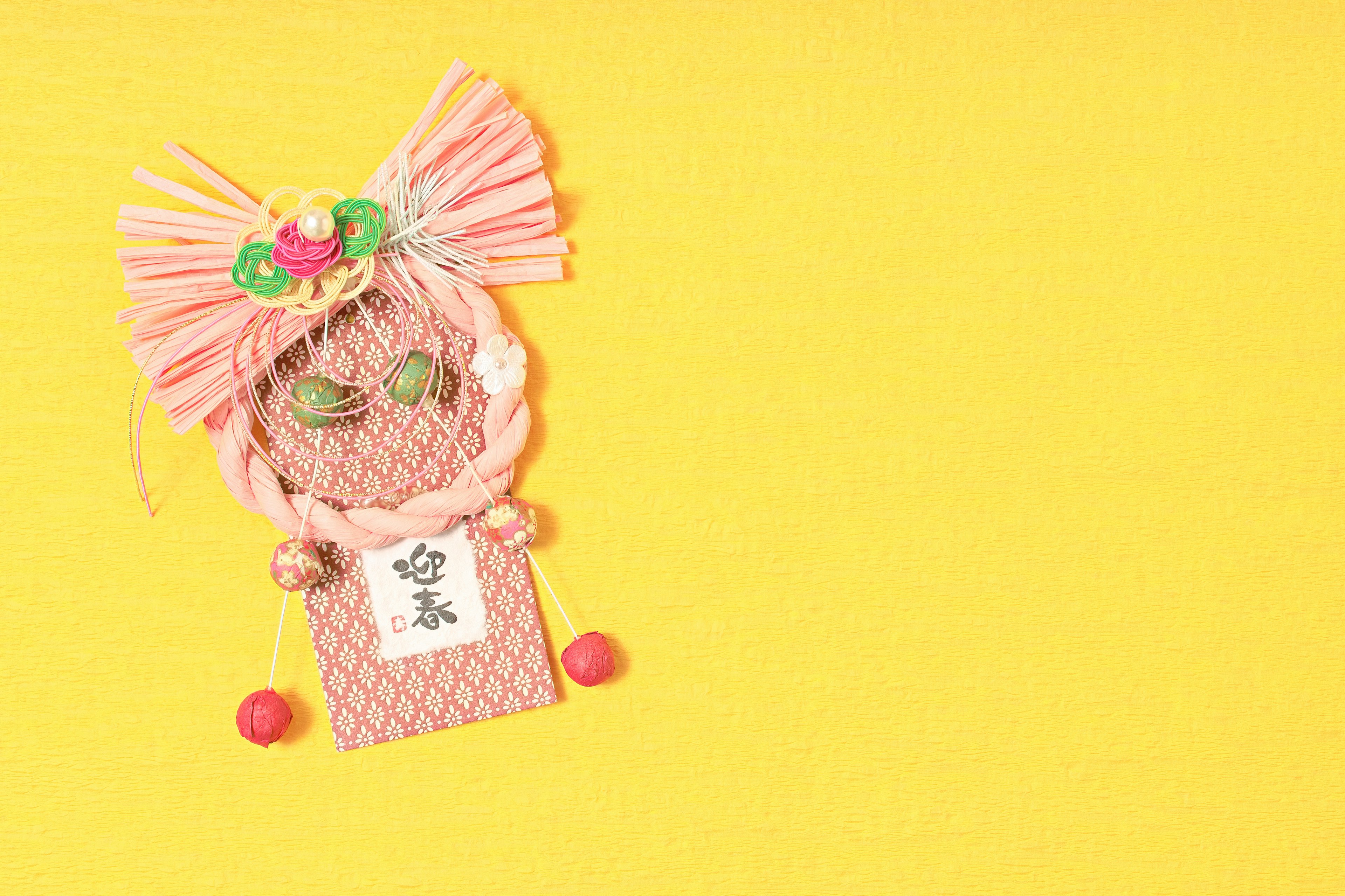 A pink decorative item with floral designs and beads on a bright yellow background