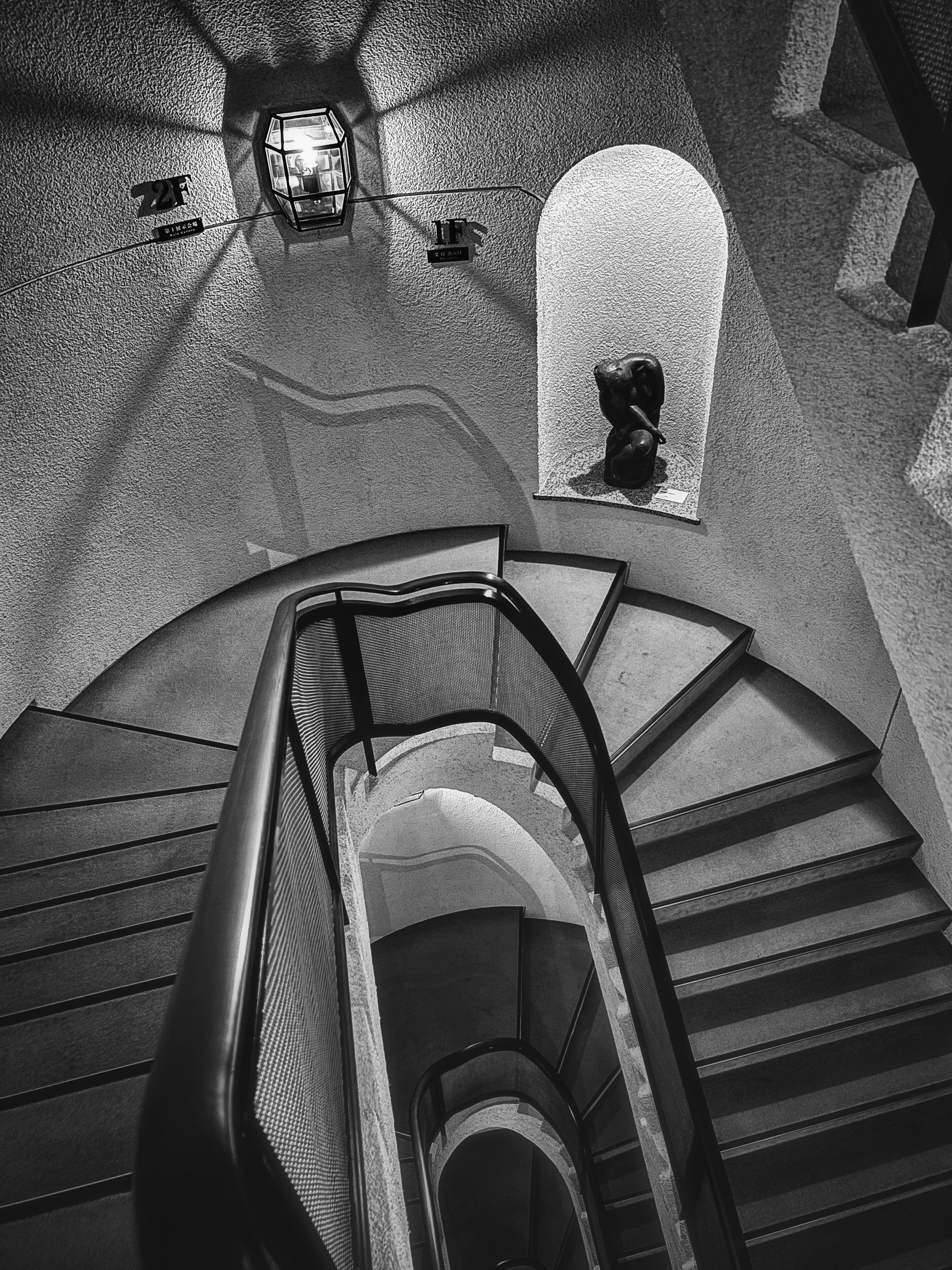 Blick von oben auf eine Wendeltreppe mit einzigartiger Beleuchtung in monochromer Farbgebung