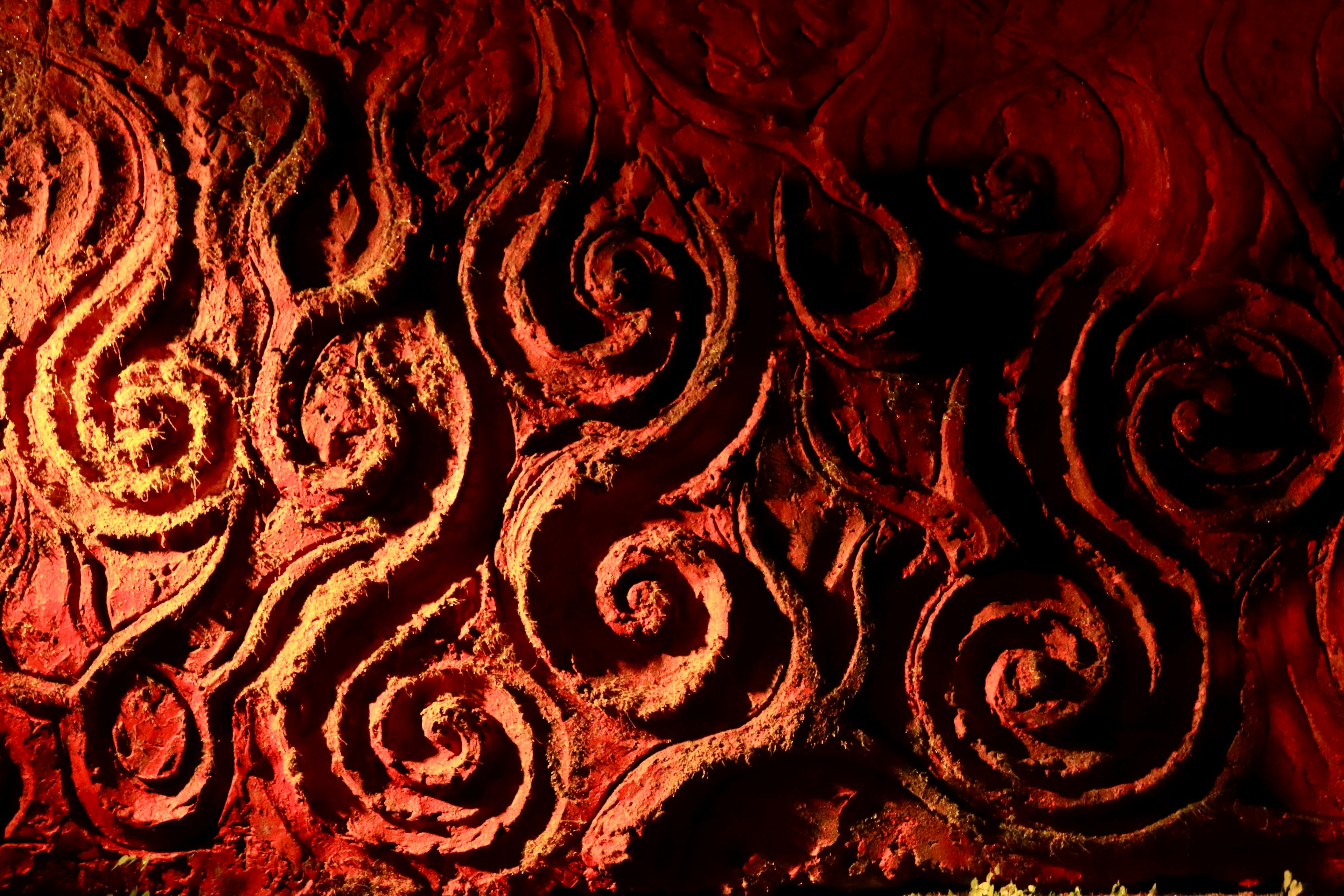 Mur avec des motifs en spirale sculptés sur un fond rouge