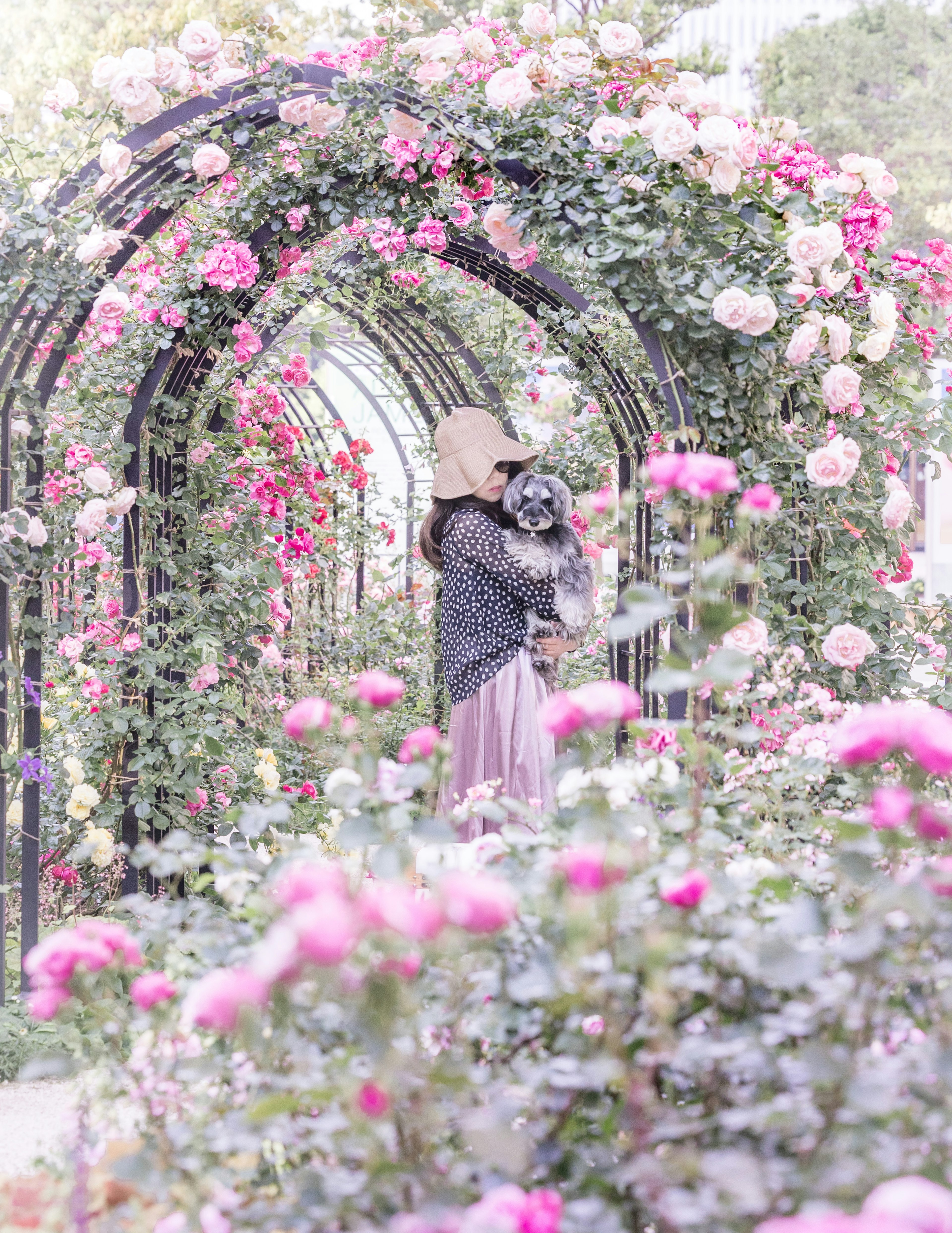 Mujer sosteniendo un perro bajo un arco floral