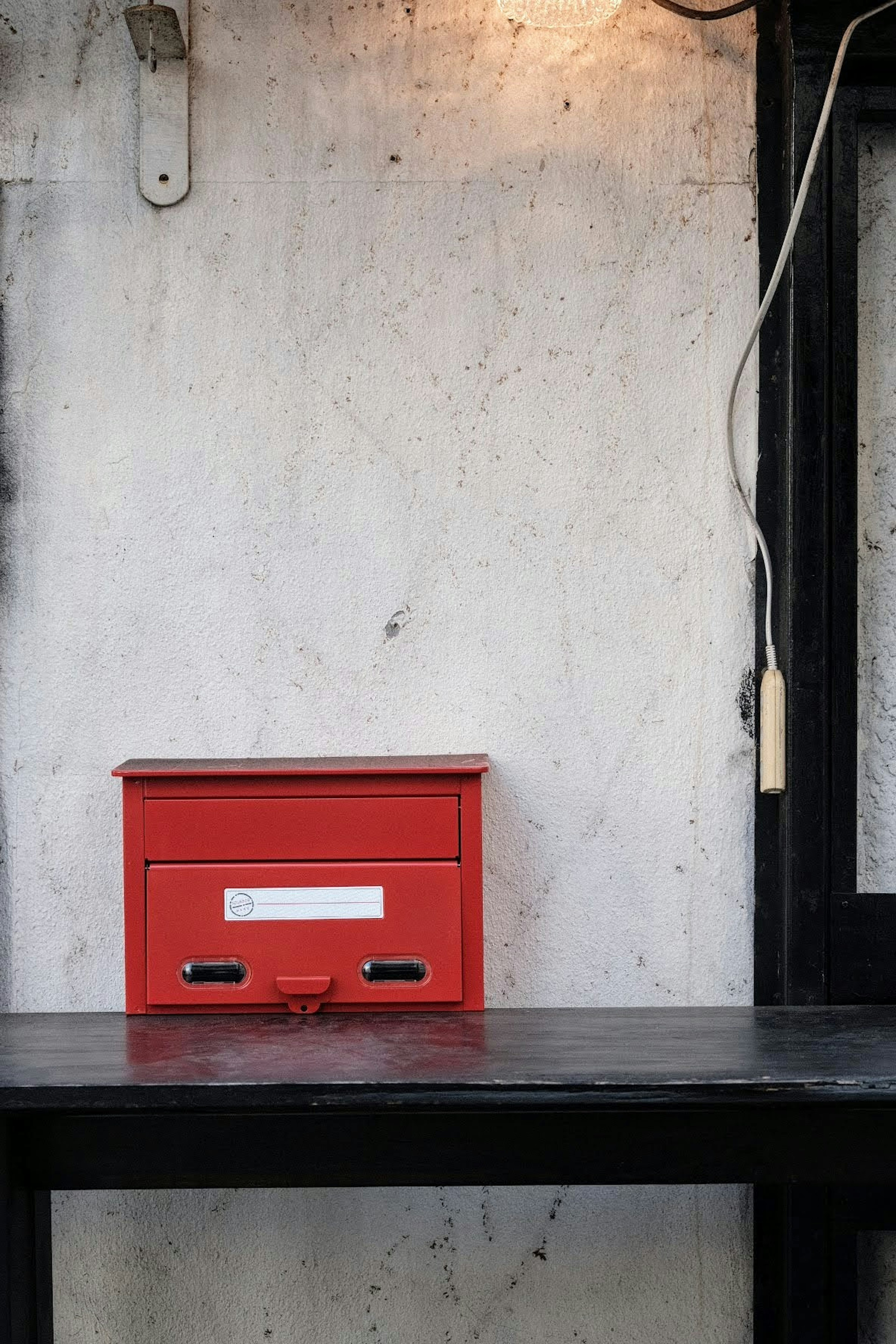 Un buzón rojo colocado sobre una mesa negra contra un fondo simple