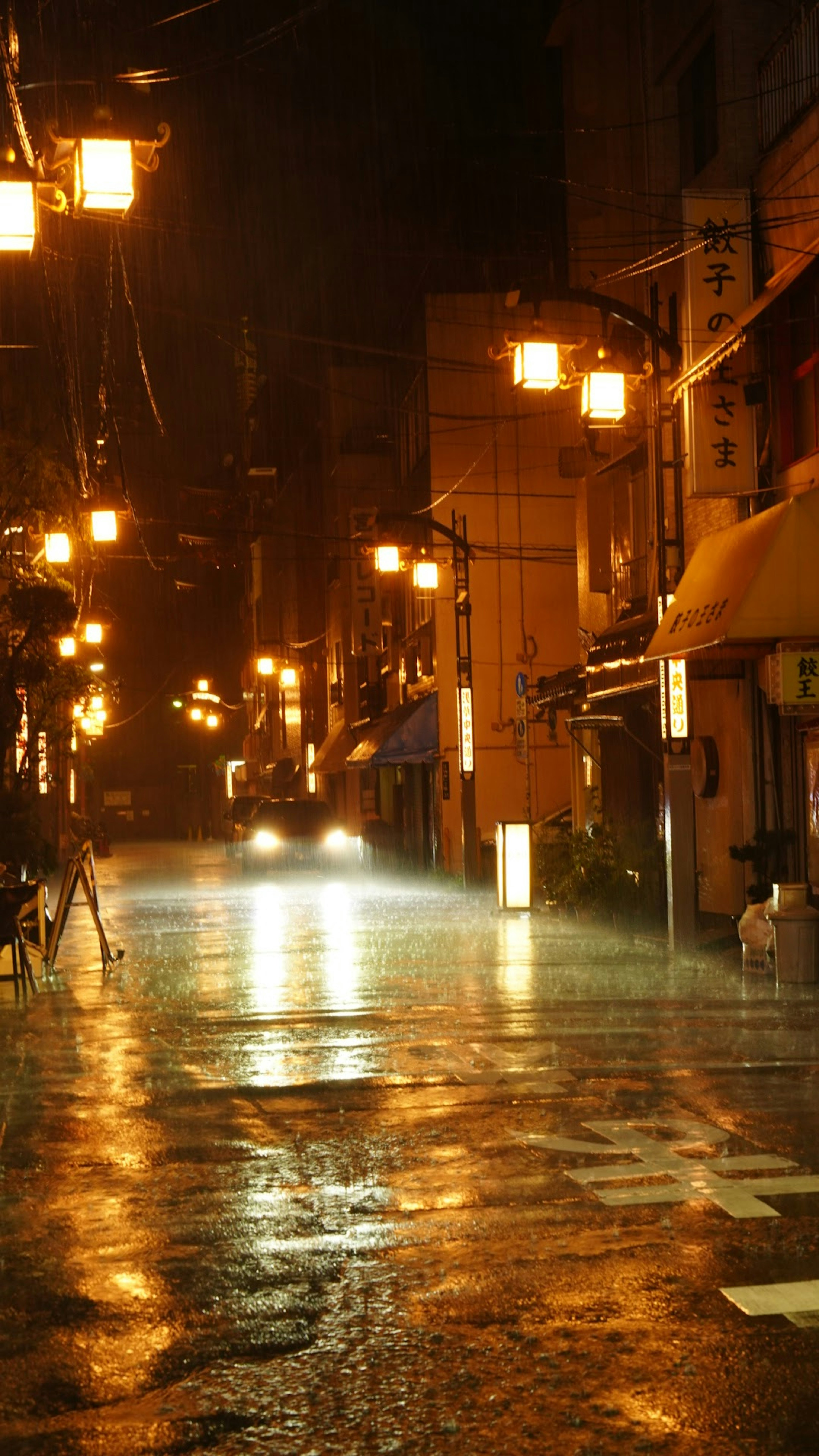 夜の雨に濡れた街道と温かい街灯が映える情景