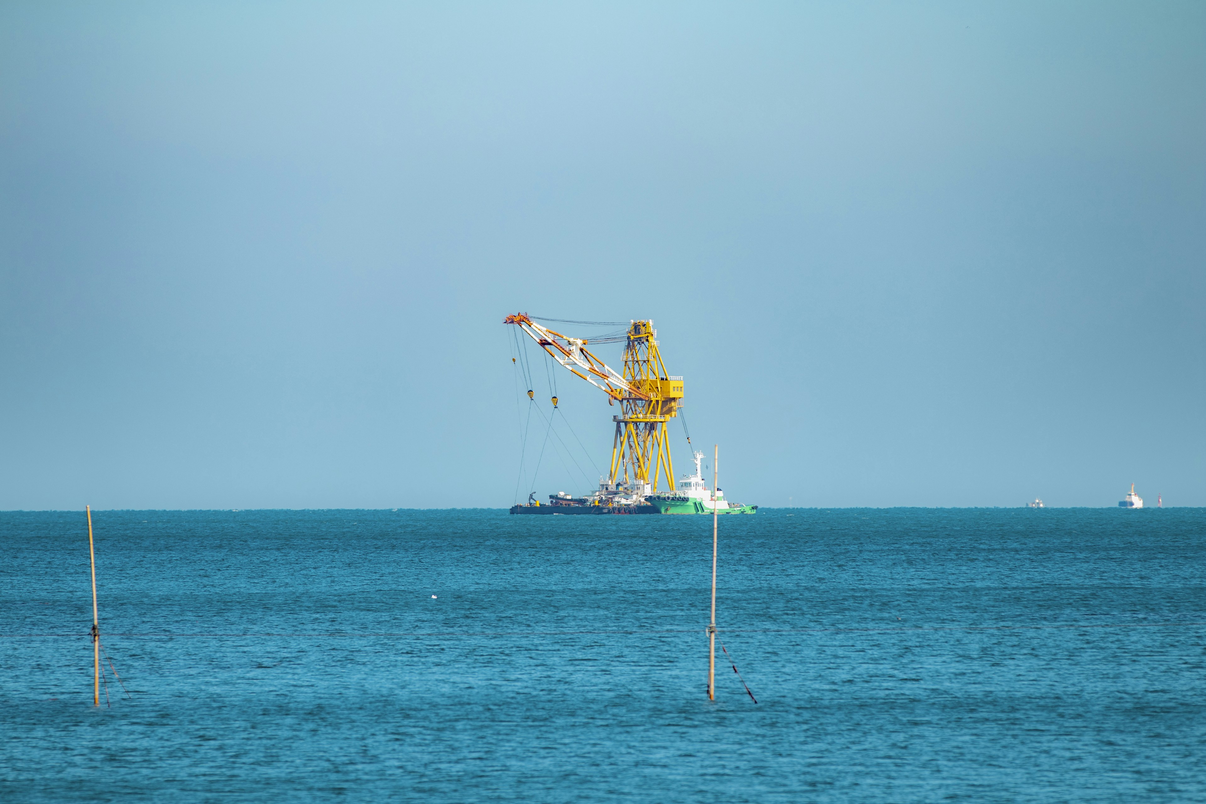 Immagine di una gru gialla e di una nave che galleggia sul mare