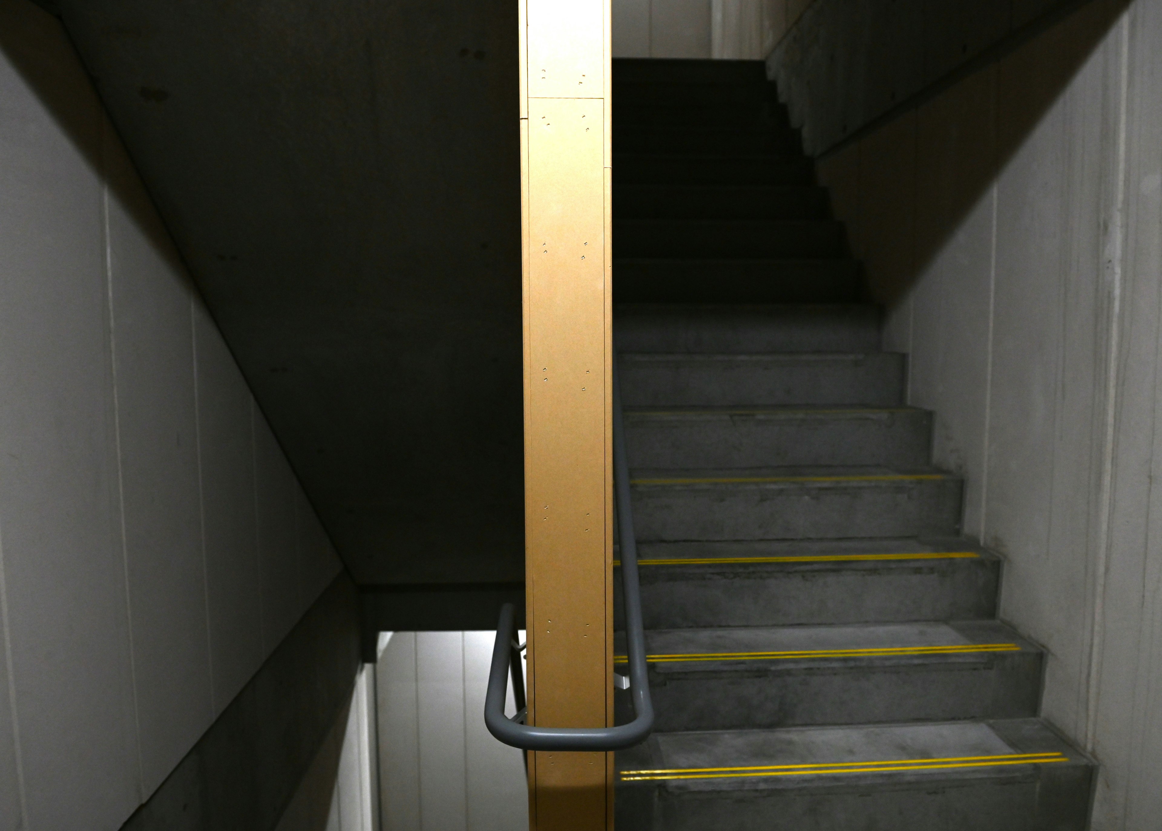 Concrete staircase featuring a metal railing and yellow lines