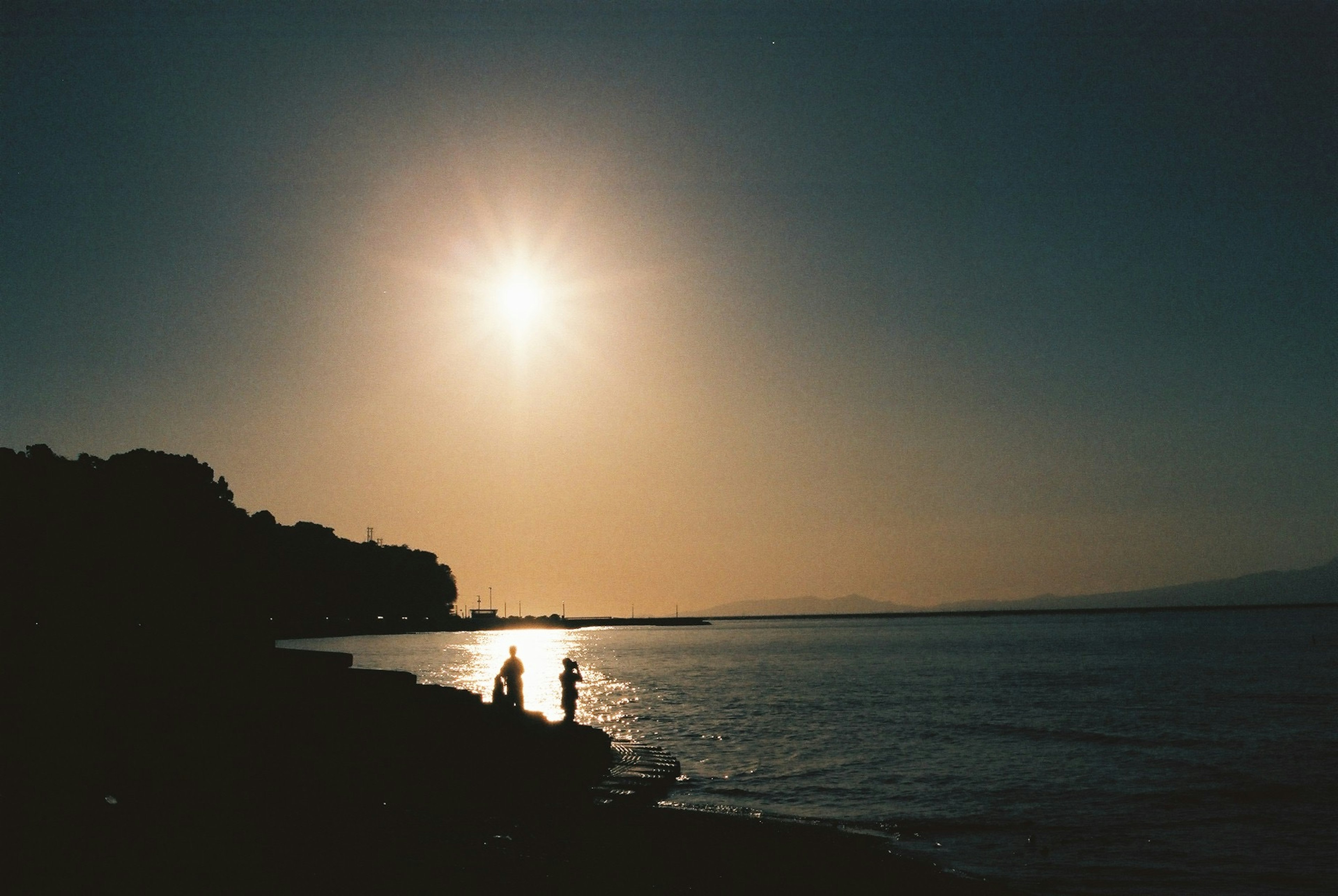 夕日を背にした海岸で二人のシルエット