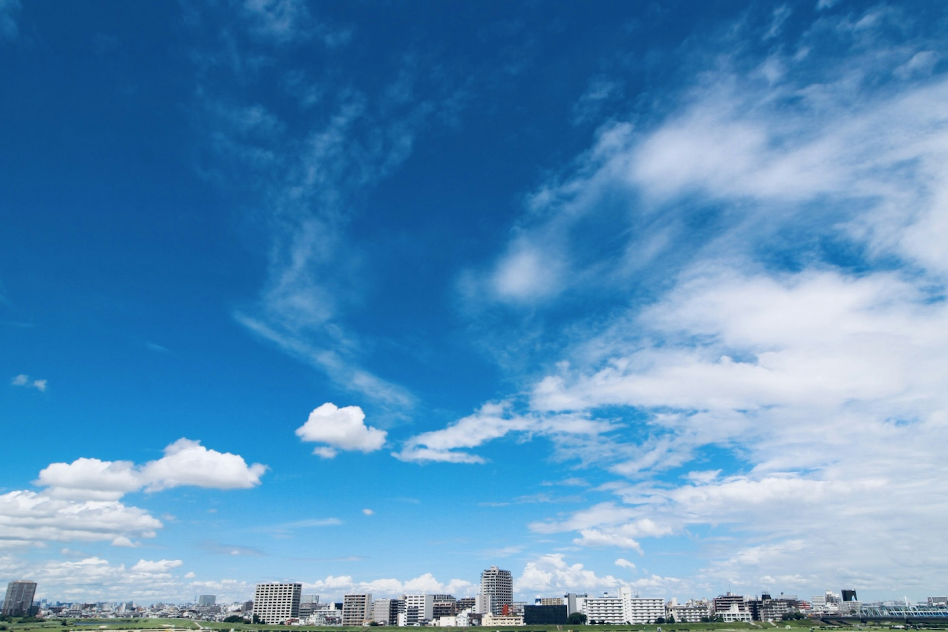 Eine Stadtsilhouette unter einem hellblauen Himmel mit flauschigen weißen Wolken