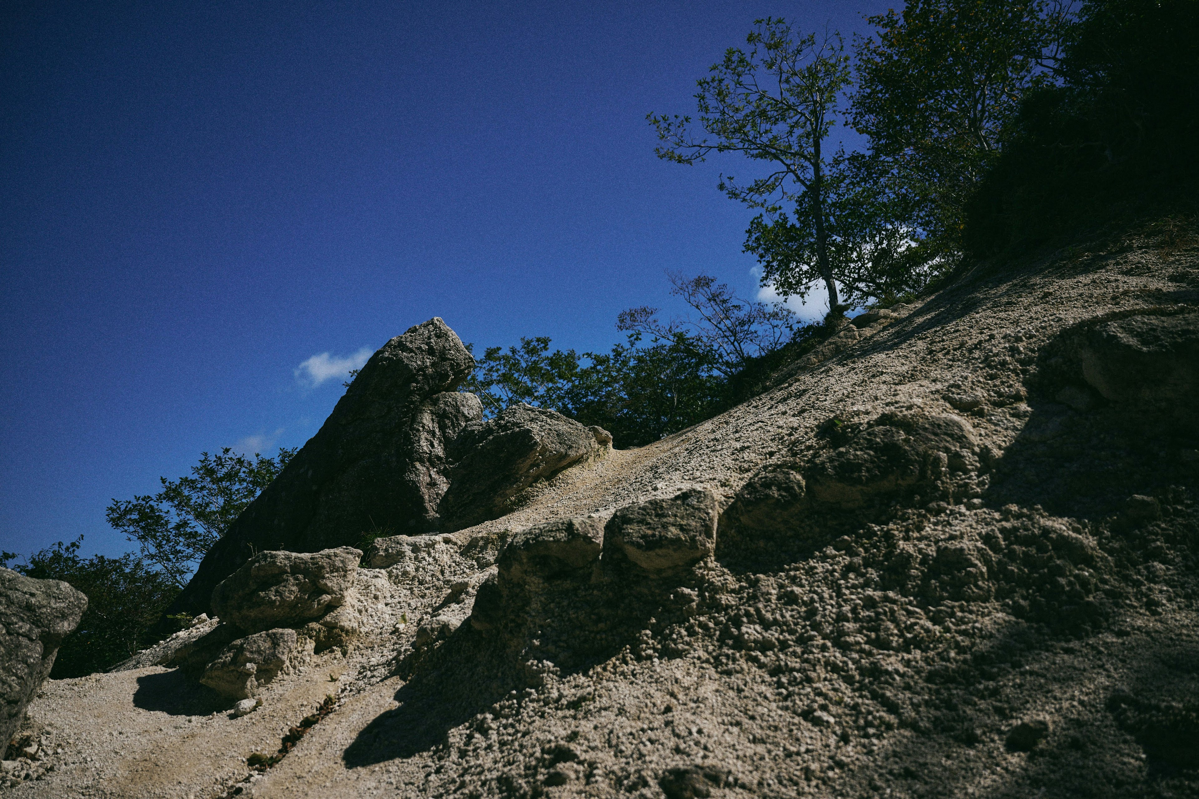 Rocky terrain with sandy slope under blue sky