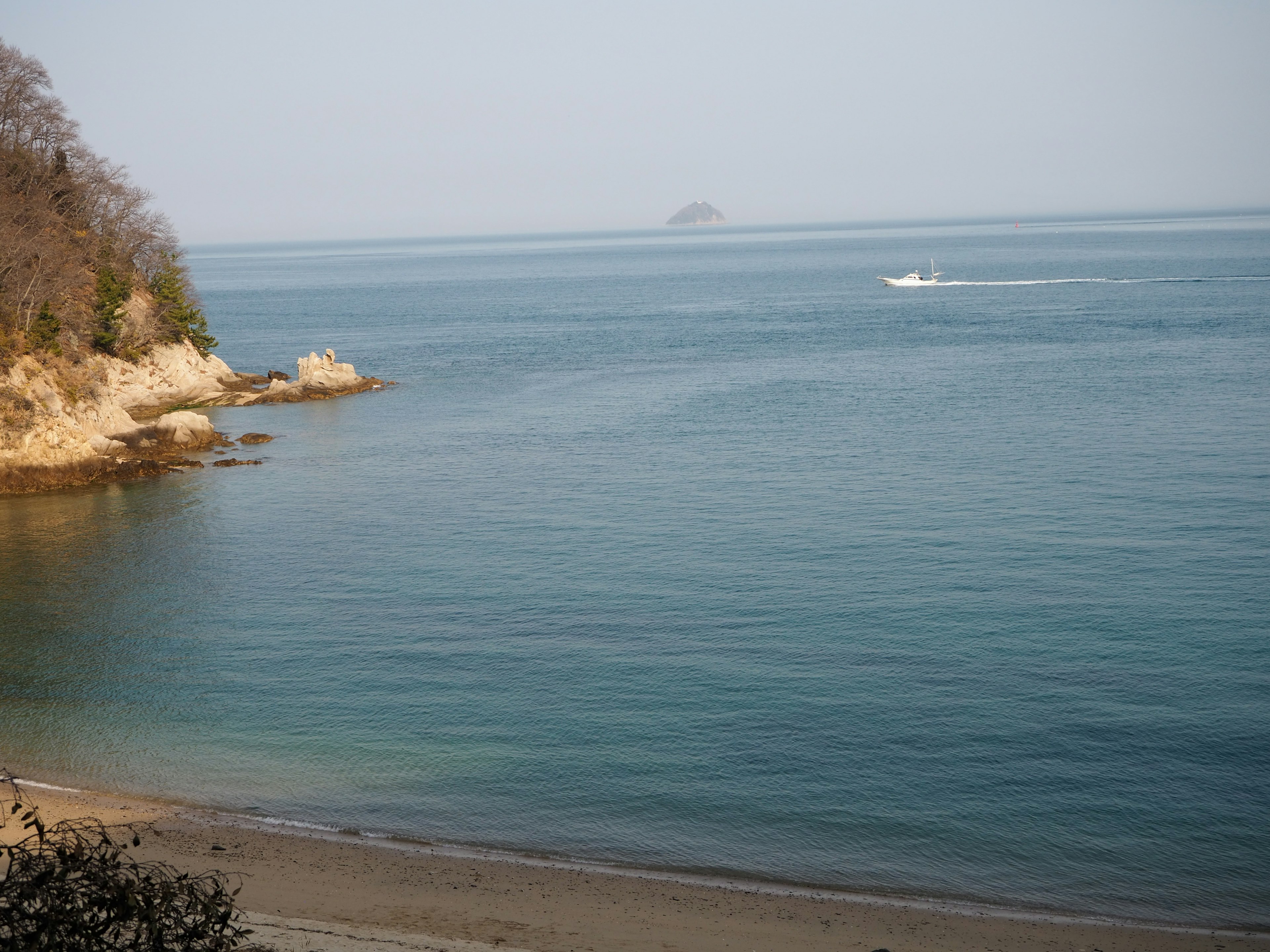 Vista de mar tranquilo y playa de arena con una isla lejana