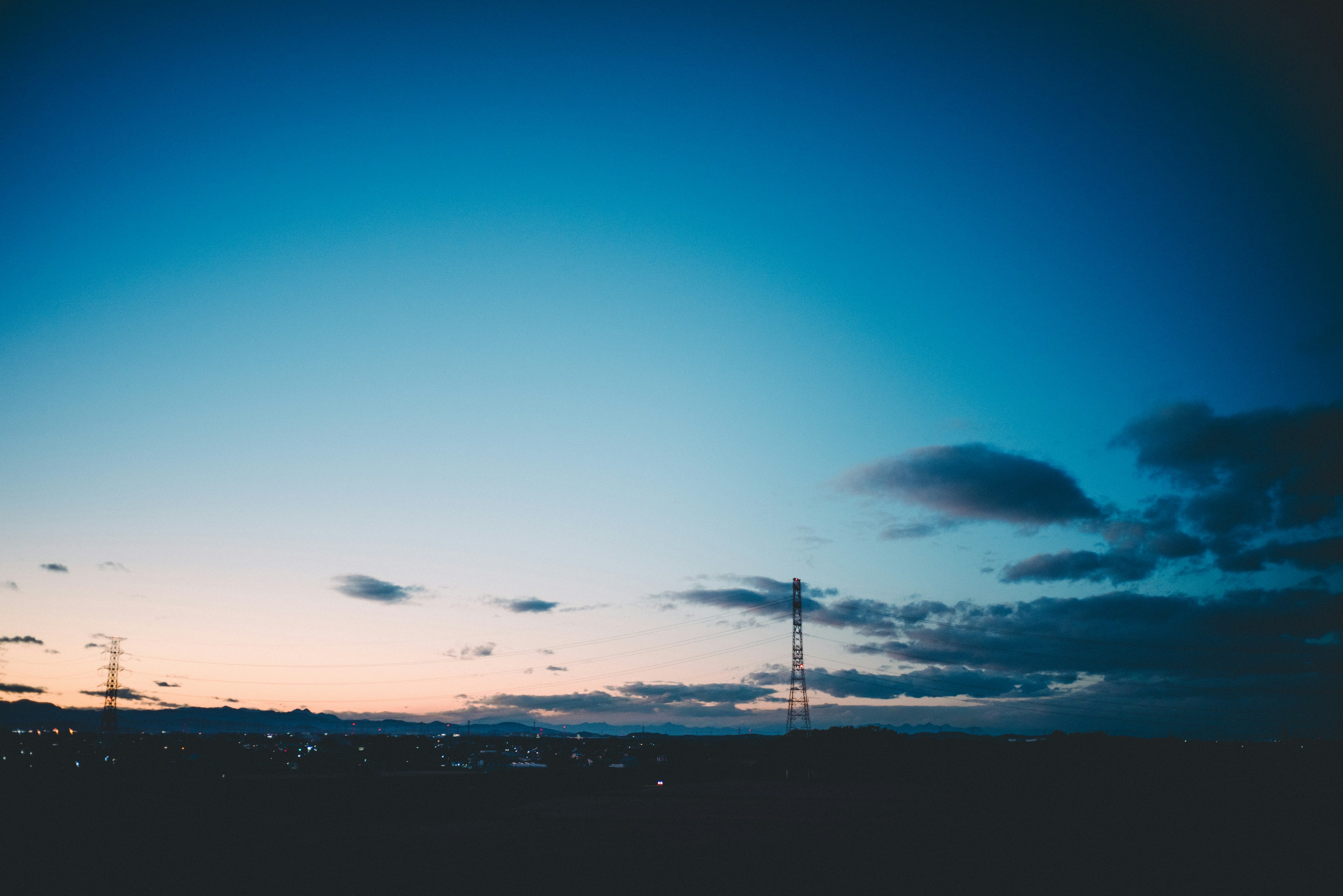 青い空に薄明かりの夕焼けと雲が広がる風景