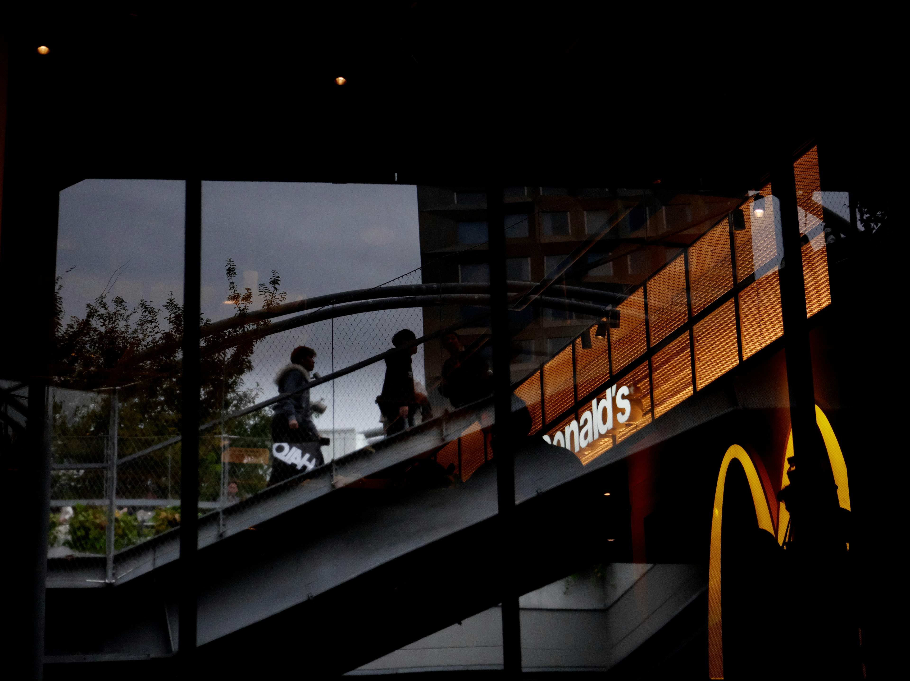 Orang-orang naik tangga dengan logo McDonald's terlihat di malam hari