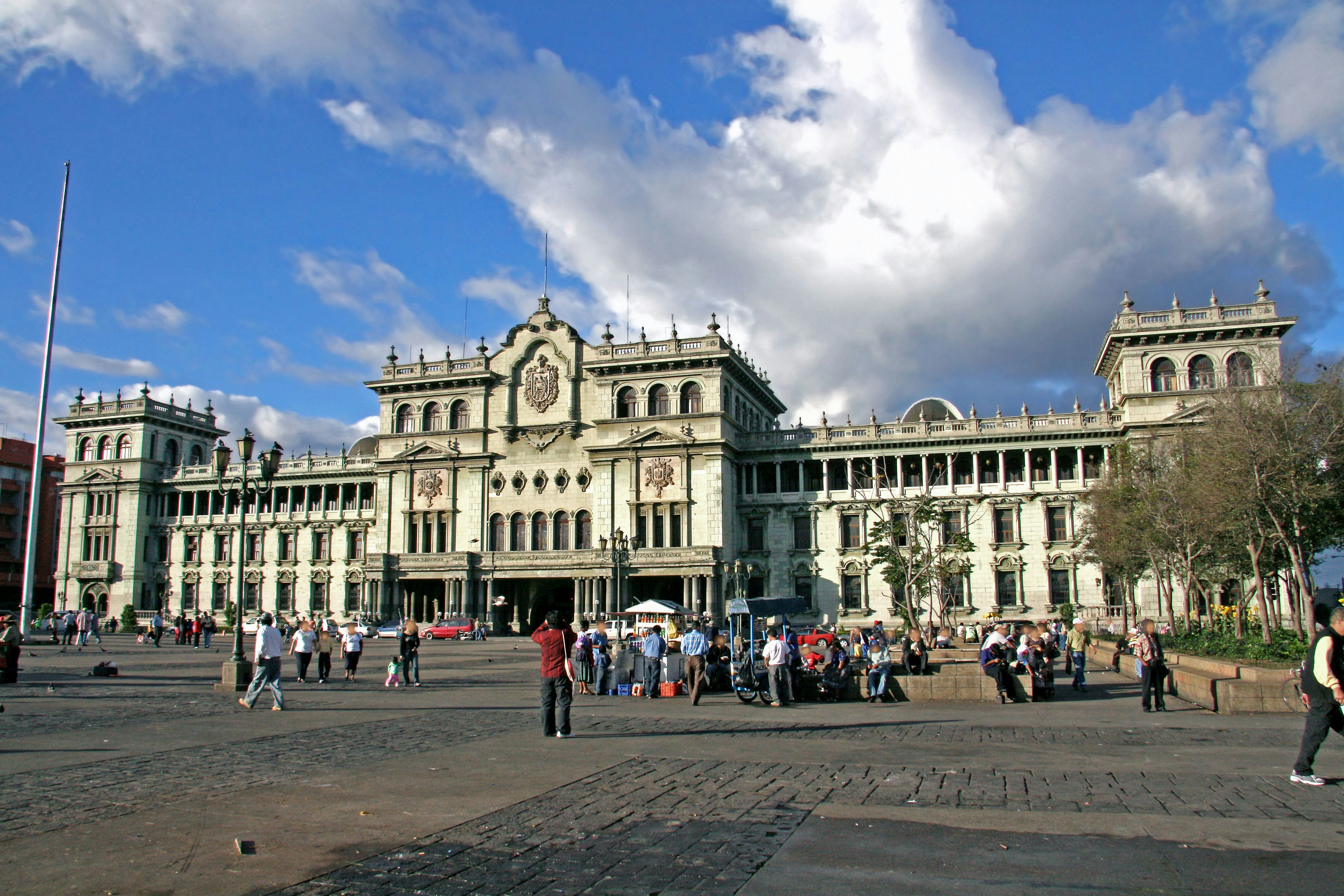 Un hermoso edificio arquitectónico con personas reunidas en una plaza bajo un cielo azul