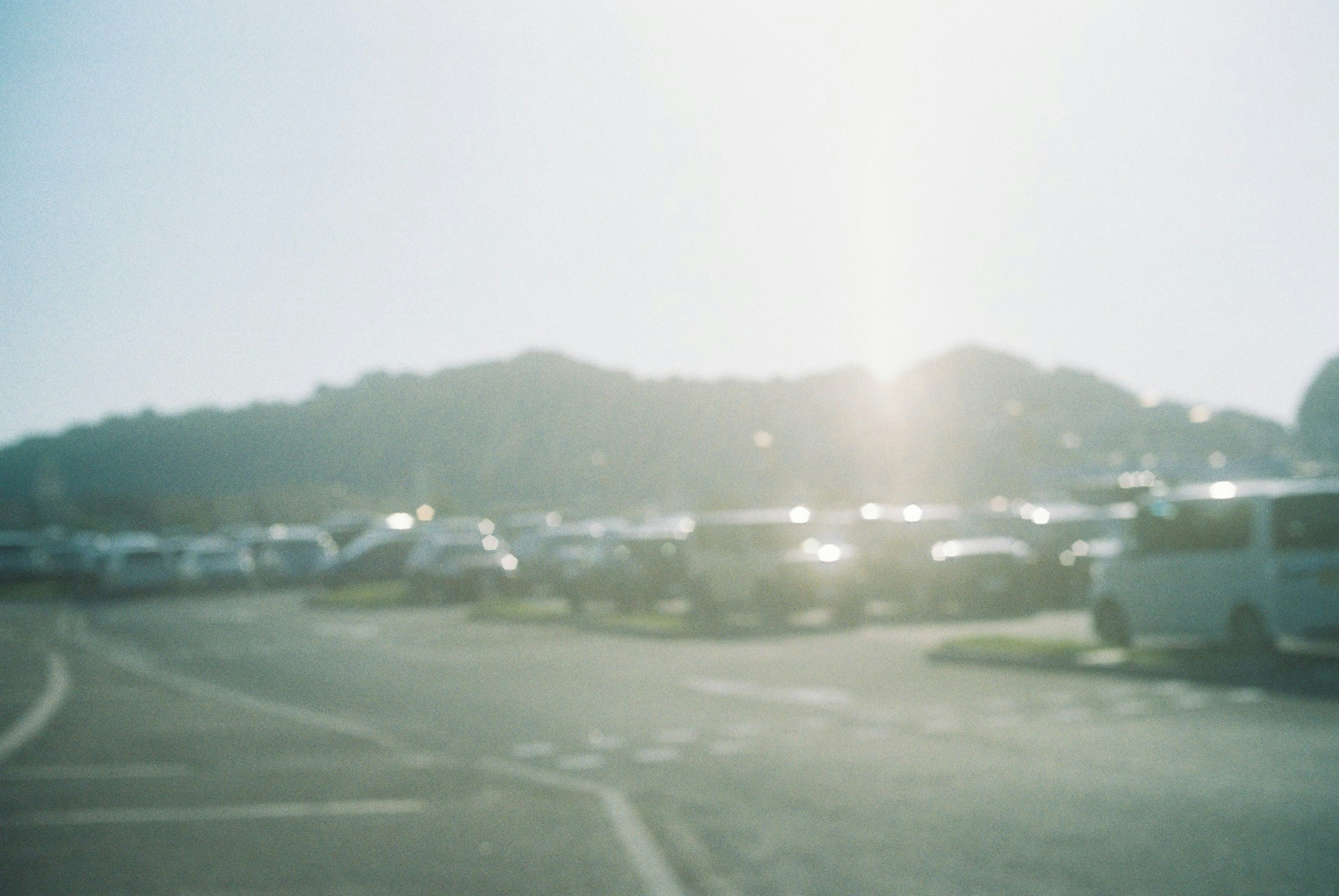 Cars parked in a lot with a silhouette of a distant hill